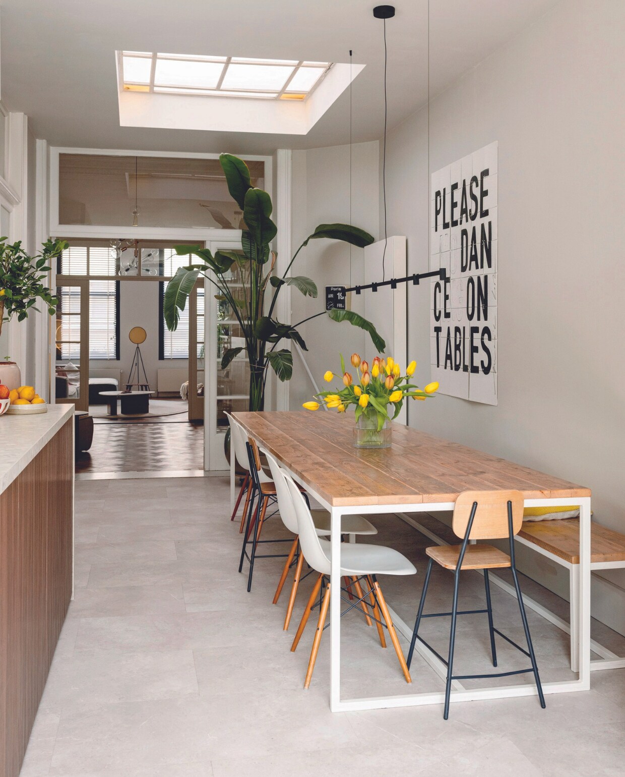 Eettafel en bank Pure Wood Design. Kinderstoelen Søstrene Grene, witte stoelen Vitra, Ixxi-kunstwerk My Deer Art Shop, lamp Trace Chandelier van Wever &amp; Ducré, fruitschaal Sissy-Boy, lage fruitschaal Sara Delesie Keramiek, vloer Triana 46210 van Moduleo. vtwonen 08-2024 | styling Ilona Jongepier | fotografie Dana van Leeuwen