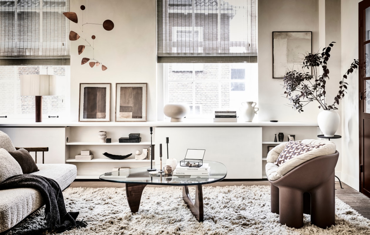 Muurverf Lime Paint in de kleur Mykonos van Bauwerk (bauwerkcolour.com). Bank FlySC2 in Smoked Oiled Oak € 5495,- (andtradition.com). Wollen vloerkleed Meadow Lvan Ferm Living, 300x200 cm € 922,99, voorraadpot Inlay van Ferm Living large €33,99, small 30,99, crèmekleurige vaas met gekronkelde handvaten Verso van FermLiving € 75,- (vtwonen.nl). Koperen mobile Lappalainen € 310,- (pantoufle-design.nl).Bruine stoel The Roly Poly Chair van Driade € 495,-, beige linnen stoelkussen € 430,-,boek Barefoot Living € 75,- (casagitane.com). Glazen salontafel Noguchi metnotenhouten onderstel € 3310,-, tafellamp Moragas van Santa Cole € 1140,-(justhaasnoot.nl). Prints Art on Paper collectie n169 en n166 in lijst, 30x42 cm € 179,-,krijt op canvas schilderij Simplicity Crackle in lijst, 50x60 cm € 499,-(mooswillemsen.com). Kleine bruine vaas € 9,99, kleine platte zwarte schotel € 15,99,kleine witte schotel € 6,99, bruin wollen kussen, 30x50 cm € 39,99, vierkant bruinbakje met geurkaars € 9,99, kleine linnen opbergdoos klein € 12,99, groot € 29,99,metalen kegelvormige kaarsendover € 17,99, glazen opbergkistje € 19,99, rondemetalen plantentafel, 30x61x27 cm (bxhxl) € 79,99, ijzeren opbergkist met dekselvanaf € 17,99 (zarahome.com). Bruine wollen plaid, 130x170 cm € 69,99 (hm.com).Alabaster theelicht € 44,99 (sissy-boy.com). Travertin boekensteun Equi € 297,-,kussen in fauteuil Geometric bordeaux van HKliving € 49,95, beige bolvaas Kabin VaseFat € 149,- (loods5.nl/design). Messing kandelaar Duca omwikkeld met rotan van Menu€ 69,- (bymolle.com). Witte vaas, zwart schaal, boeken privébezit. vtwonen 11-2022 | fotografie Sjoerd Eickmans | styling Kim van Rossenberg | uitvoering Richard van Meerveld