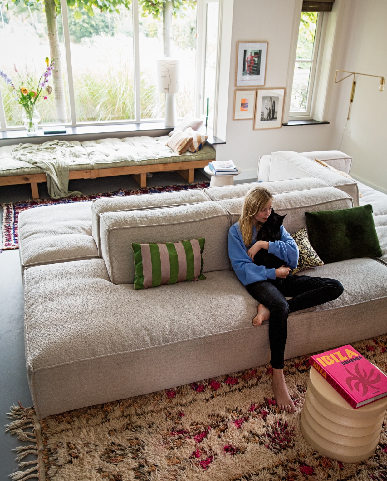 Erkerbank op maat gemaakt. Lamp in erker en bijzettafel HKliving. Lamp aan muur Bloomingville. Elementenbank Square van Easy Sofa. Kussens mix van Hay, Bungalow, HKliving en Ferm Living. Kleden vintage berbers via Etsy. vtwonen 04-2022 | styling Ilona Jongepier | fotografie Dana van Leeuwen | visagie Djolien de Kreij
