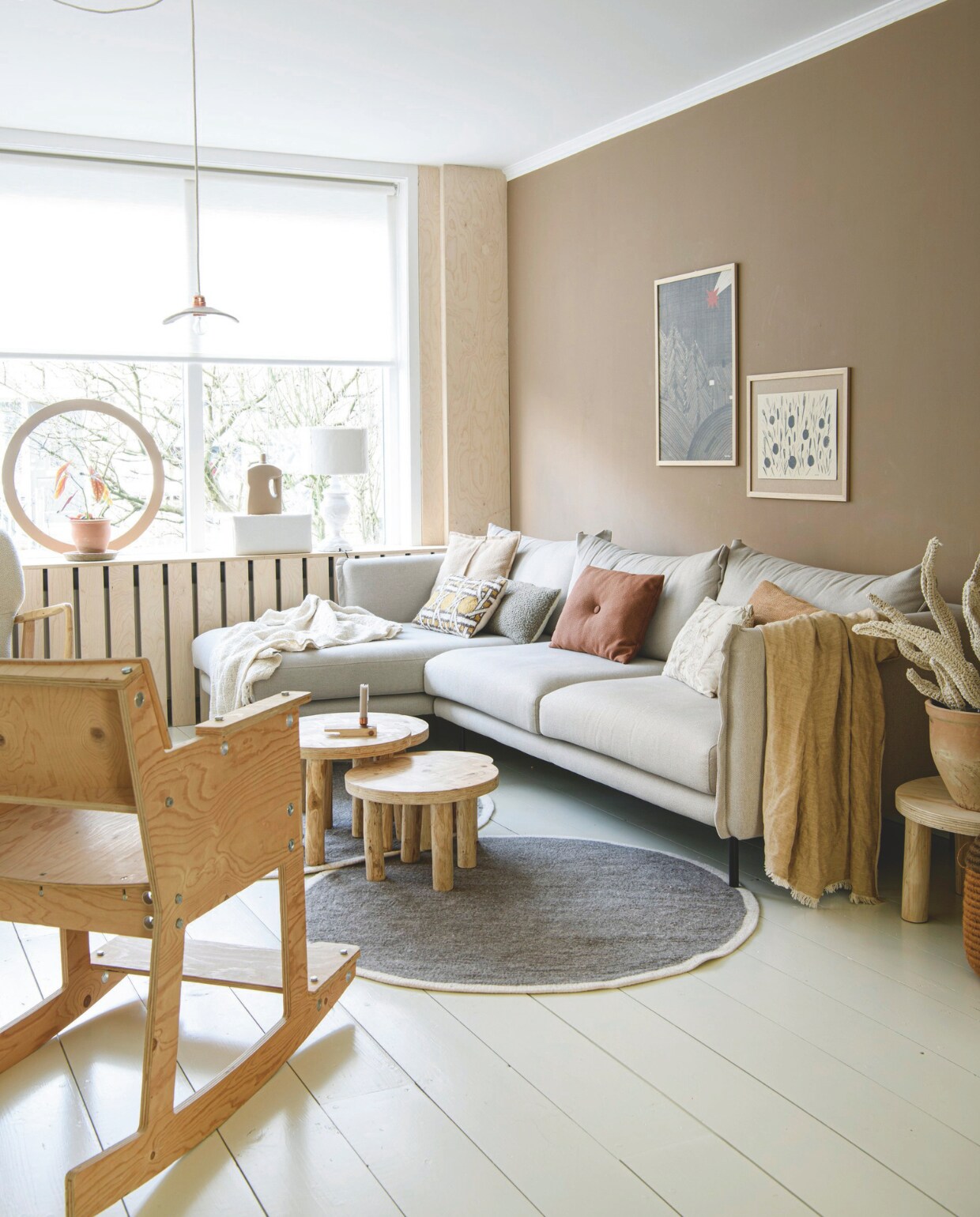 Muurverf E420.50 van Sikkens, vloer vuren delen, radiatorombouw berken multiplex, rolgordijn Leen Bakker. Kleed en bijzettafels Huis &amp; Grietje. Pot Esschert Design, plant Intratuin, vaas kringloop, zelf geverfd. Cirkel in raam, doos en lamp zelfgemaakt. Bank Lumz, witte sprei Juffrouw Jansen Lifestyle. Kussens twee links en middel Loods 5, derde van links Stapelgoed, twee rechts gemaakt door moeder van vriendin en Søstrene Grene. Bruine sprei H&amp;M home. Posters Ted &amp; Tone en Huis &amp; Grietje, lijsten Jysk. Houten stoel Leen Bakker, schommelstoel Piet Hein Eek. Gehaakte plant Anne-Claire Petit, pot Action. Hanglamp Muskhane. vtwonen DIY 9 | styling Janneke Peters | fotografie Louis Lemaire