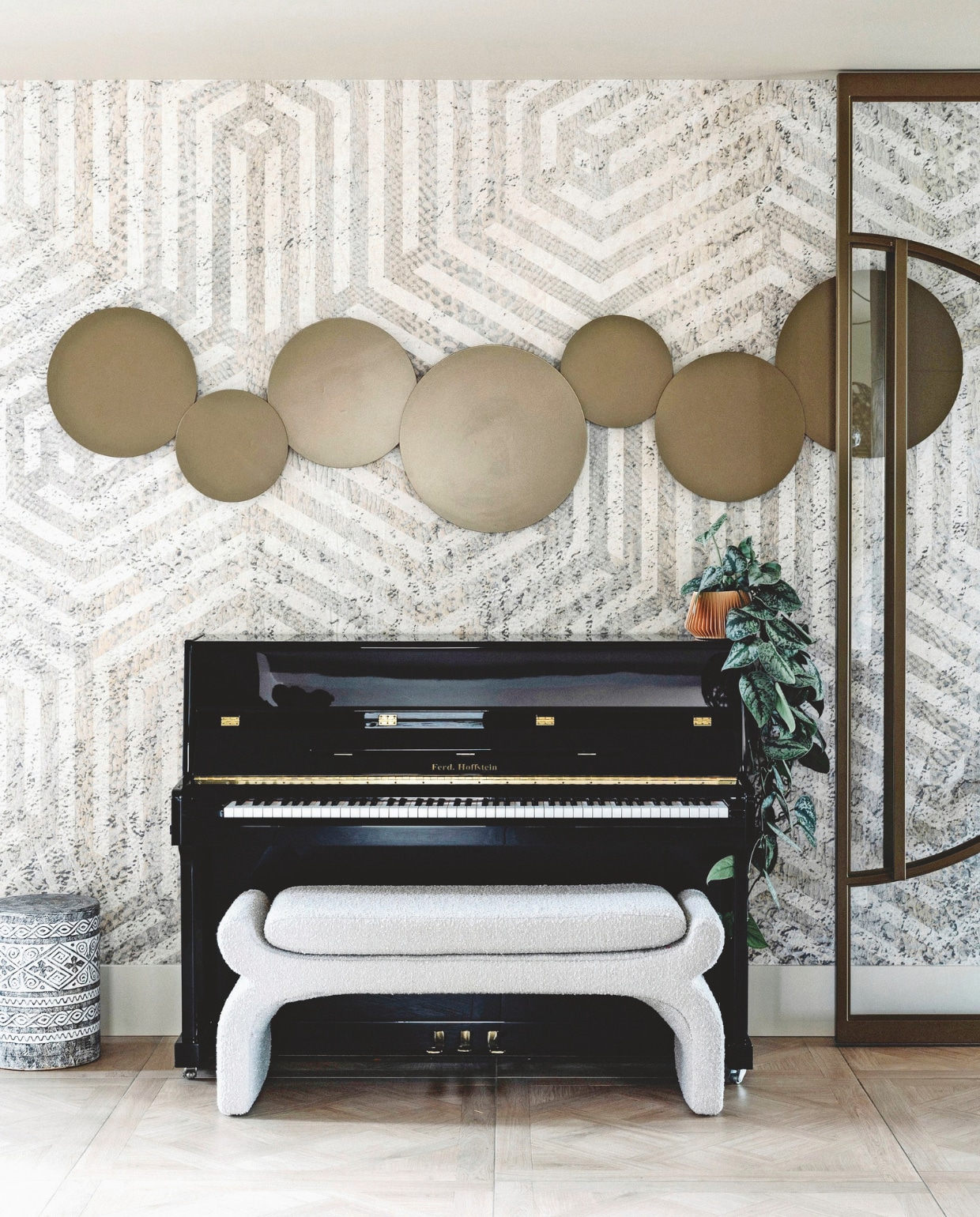 Boven de piano hangt een ronde lamp die Kim samen met Querine van Alen van De Ontwerpster en Halo Lighting ontwierp. De pianokruk is van Kötter Living. Het behang is een eigen ontwerp van Poespas. stijlvol wonen 9-2024 | Fotografie Stefanie De Neve
