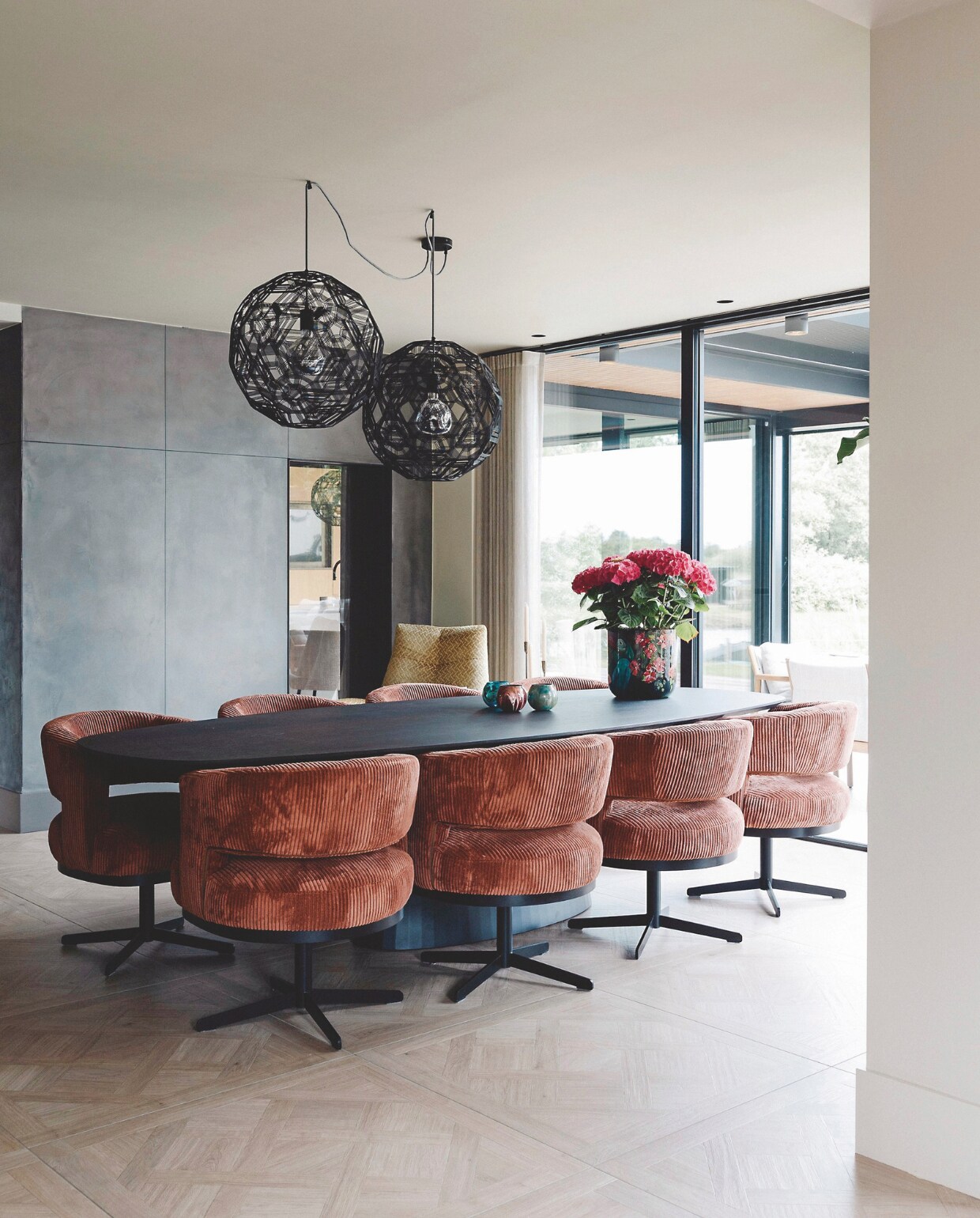 De eetkamer met een grote tafel, comfortabele stoelen en ronde lampen, allemaal via Kötter Living. stijlvol wonen 9-2024 | Fotografie Stefanie De Neve