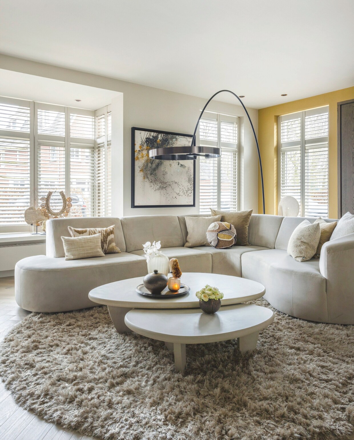 De bank en de kussens zijn van Violier at Home, net als het carpet. De stucco salontafels van Duran Interiors, de booglamp van Occhio en de twee hoge kasten van Keijser&amp;Co zijn door Violier at Home geleverd. Het behang op de wand van de televisie van Élitis en het kunstwerk achter de bank van Umo Art &amp; Design zijn aangeschaft via Violier at Home. stijlvol wonen 10-2024 | foto Anne Gambon