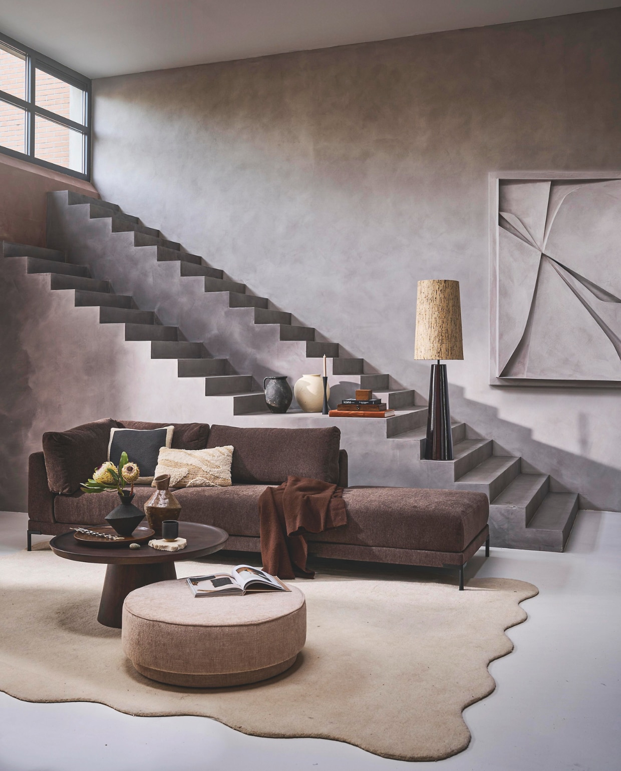 Elementenbank Couple lounge-element links (•4) in chocoladebruin, 200x100x89 cm (bxdxh) € 1399,-. Mangohouten salontafel Coffee A Gogo (•6) in walnootfineer, 90x40 cm (Øxh) € 499,-. Polyester poef Pearl XL (•5) in naturel melange, 80x28 cm (Øxh) € 199,-, verkrijgbaar in meerdere stoffen. Metalen kandelaar in matzwart, vanaf 16 cm (h) € 16,95.M.m.v. artinreturn.nl (schilderij), thefarm-shop.nl (verf muur Bold Basalt, verf trap Consious Concrete), zarahome.nl (vazen op tafel), layeredinterior.com (vloerkleed Scallop), vtwonen.nl/shop (lamp en lampenkap van HKliving). Overig privébezit. vtwonen 10-2024 | styling Cleo Scheulderman | fotografie Jeroen van der Spek