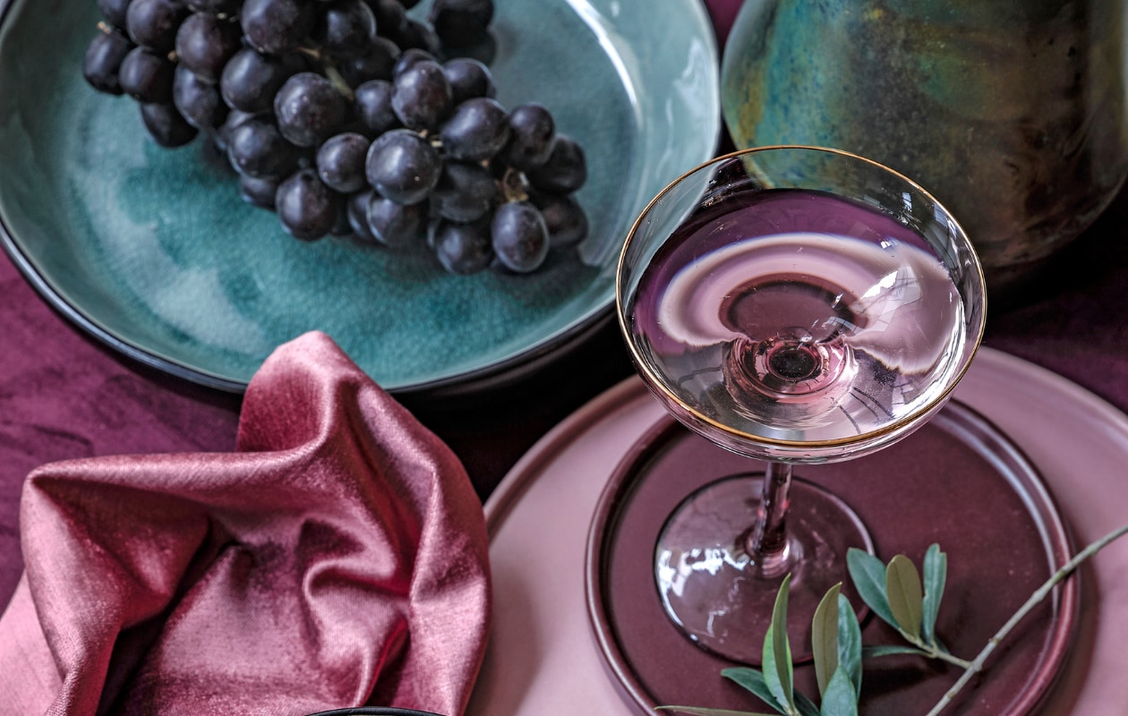 Pleat van Bloomingville € 155,- (vtwonen.nl). Donkerroze velours tafelloper € 14,99, oudroze bord € 9,99, aubergine kleurig bordje € 4,99, cocktailglas roze en goud € 7,99 (hm.com). Grijsgroen pastabord Crackle € 8,-, zwart-okergeel schaaltje Crackle € 4,- (kwantum.nl). vtwonen 02-2019 | styling Moniek Visser | fotografie Peggy Janssen