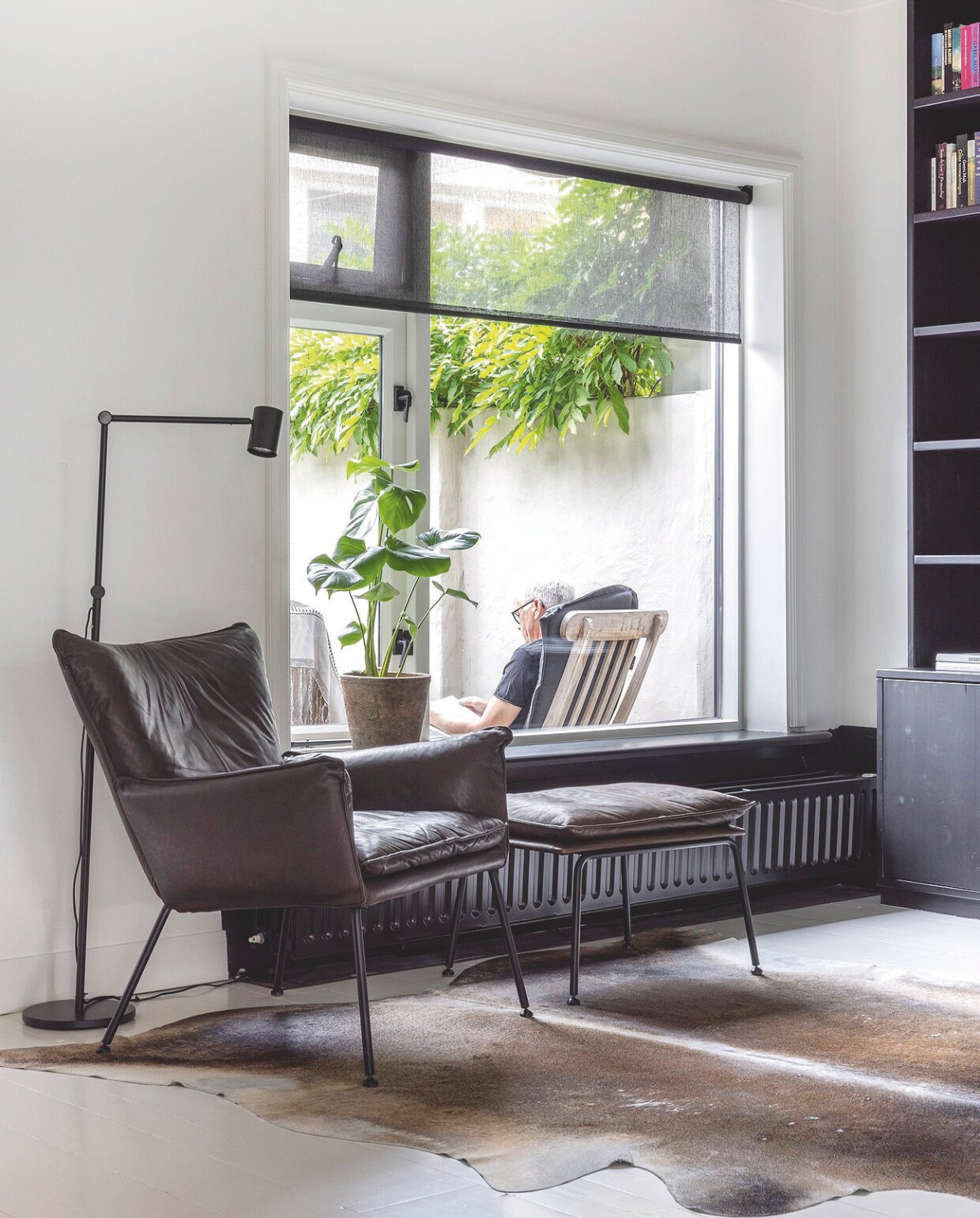 Fauteuil Eijerkamp, lamp Ikea. Boekenkast op maat gemaakt door Arja’s broer, Ad van de Graaf, en geschilderd in Ral 9005. vtwonen landelijk 06-2024 | fotografie Anneke Gambon