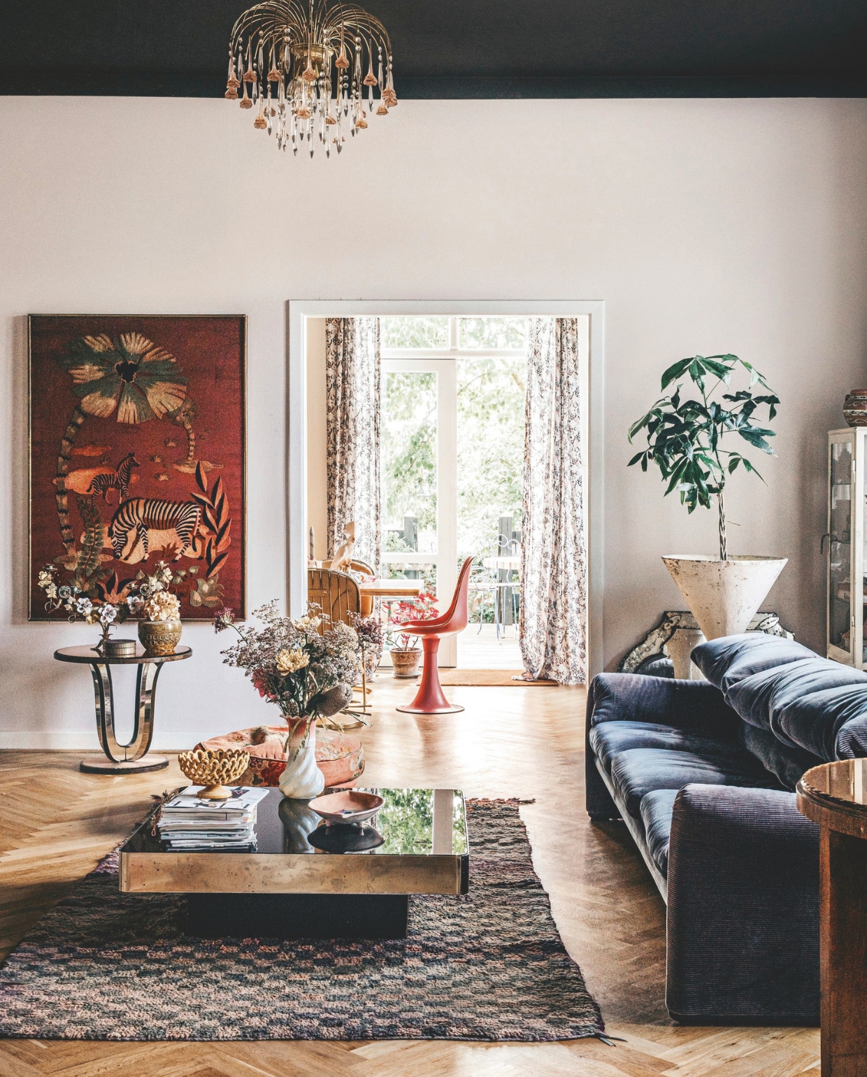 Oude Franse tissuedozen gevonden op een Franse vlooienmarkt, spiegel vintage Murano. Bank, salontafel, witte vaas, bijzettafel, vaas op bijzettafel, schaal en schilderij vintage. Vintage plantenbak ontworpen door Willy Guhl. Alle accessoires in huis zijn door Maria zelf via contactpersonen voor haar winkel of op vlooienmarkten in België, Frankrijk en Italië gevonden. vtwonen 11-2024 | styling Lina Vertus | fotografie Isabell Wedin