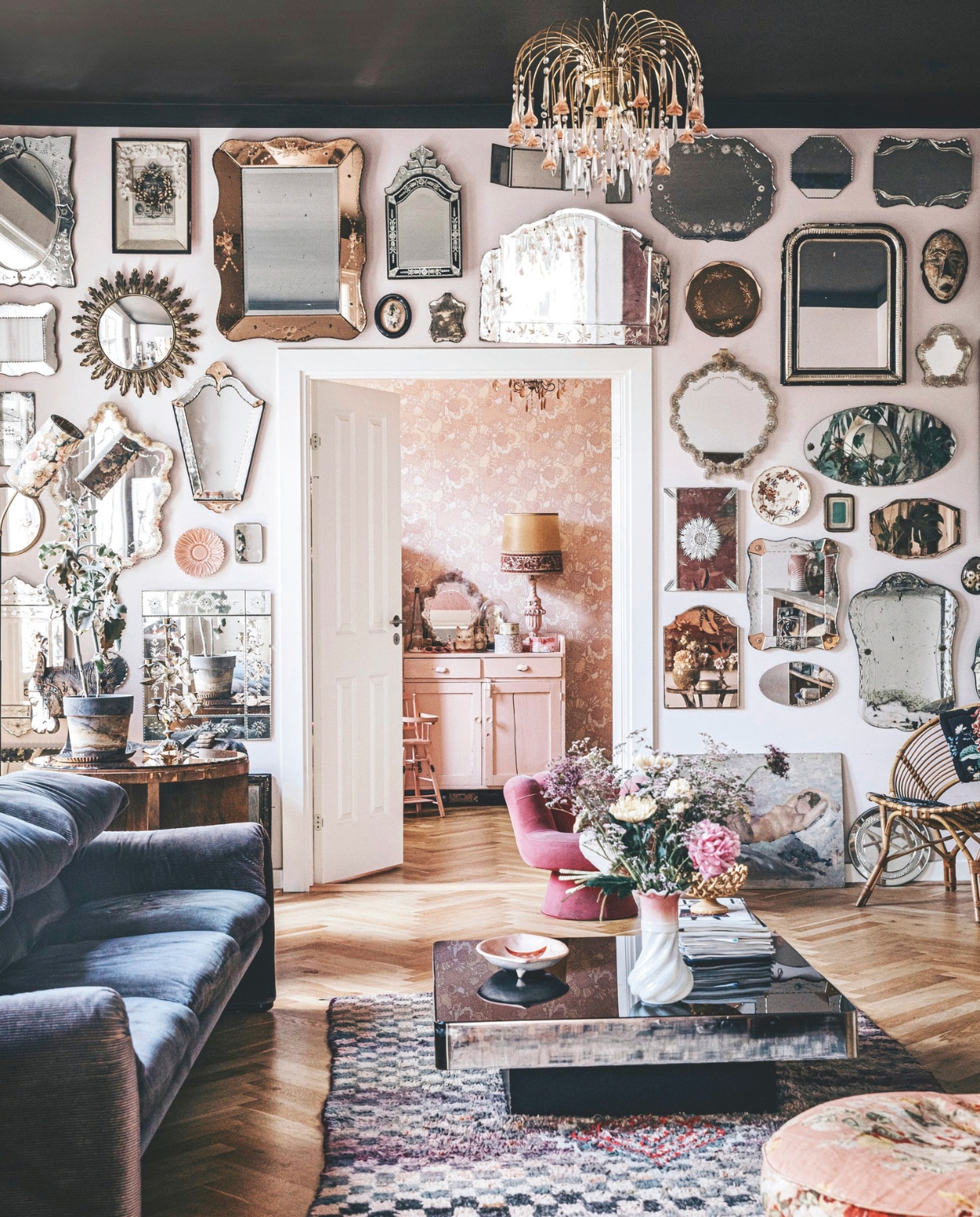 Bank, Marokkaans kleed, poef, witte vaas, rotan stoel vintage. Spiegels zijn op verschillende plekken gekocht. Maria verkoopt vergelijkbare spiegels in haar winkel Boho Habits. Roze lage stoel Boho Habits. Ronde bijzettafel, roze commode gevonden in Frankrijk, lamp op commode vintage. vtwonen 11-2024 | styling Lina Vertus | fotografie Isabell Wedin