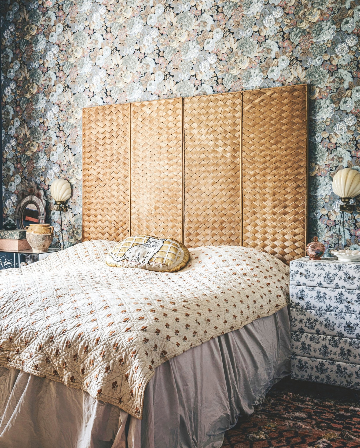 Hoofdboord van het bed en kussen op bed vintage. Vintage behang en vintage muurlampen uit Frankrijk. vtwonen 11-2024 | styling Lina Vertus | fotografie Isabell Wedin