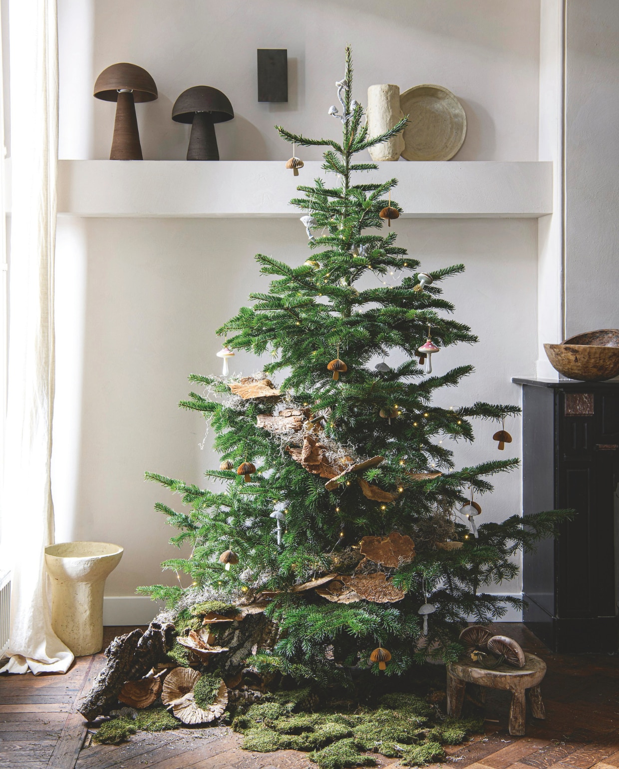 Wandverf in Amalfi van We Are Wow Makers, per liter € 55,-, keramische tafellampen Fungi van Claire Horsten Ceramics, per stuk € 499,- (justanothershop.nl). Witte papier-maché pot € 22,50, witte papier-maché schaal € 17,60, witte papier-maché schaal op voet € 59,-, houten kruk uit India € 149,- (hetkabinet.nl). Natuurlijke kerstboom Nordmann, 240 cm (h) € 55,- (buitengoeddeboomgaard.nl). Gedroogde zwammen (bloemschikwinkel.nl).  Fluwelen paddenstoelen op kruk € 29,32 (hotskwash.com). In boom: wit paddenstoelornament met drie hoeden € 15,-, wit paddenstoelornament, set van 4 € 29,- (fermliving.nl). Papieren ornament Fungi van Broste Copenhagen € 8,50 (livingandcompany.com). Paddenstoelornament op clip van House of Seasons, set van 2 € 4,- (vtwonen.nl/shop). Glazen kerstbal Mushroom Small € 11,95 (klevering.com). Overig privébezit. vtwonen 12-2024 | styling Marit Saladini | fotografie Louis Lemaire