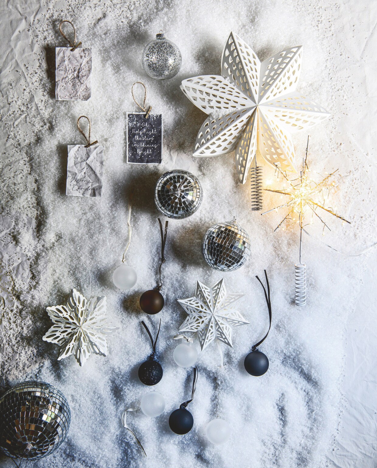 Minicanvas per met acht kaarten, touw en knijpers € 19,95 (mo-ca.nl). Glazen kerstbal met glitter van House of Seasons, set van 3 € 4,-, discoballen van House of Seasons, 10 cm (Ø), set van 2 € 5,50, en 15 cm (Ø) € 6,- (vtwonen.nl/shop). Witte kartonnen sterpiek van House Doctor, 30 cm (Ø) € 27,- (connox.com). Piek Glow white met ledlicht van House Doctor € 44,95 (strong-desire.nl). Papieren sneeuwster Falke van Broste Copenhagen € 12,40 (villamadelief.nl). vtwonen 12-2024 | styling Marit Saladini | fotografie Louis Lemaire