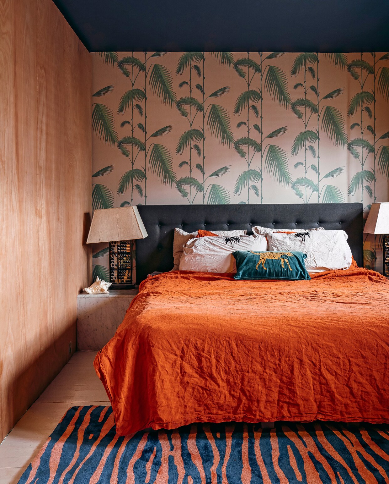 Verf plafond Deep Steel, Histor. Behang Palm Jungle van Cole &amp; Son. Marmeren nachtkastjes en lampen vintage. Schelp souvenir uit de Dominicaanse Republiek. Linnen dekbedovertrek Casa Comodo. Panterkussen The Pillow Room. Kussenslopen Crisp Sheets. De houten wand is de zijwand van de inloopkast. Kleed The Zebra Rug van Studio Vacay. vtwonen 11-2020 | fotografie Muk van Lil