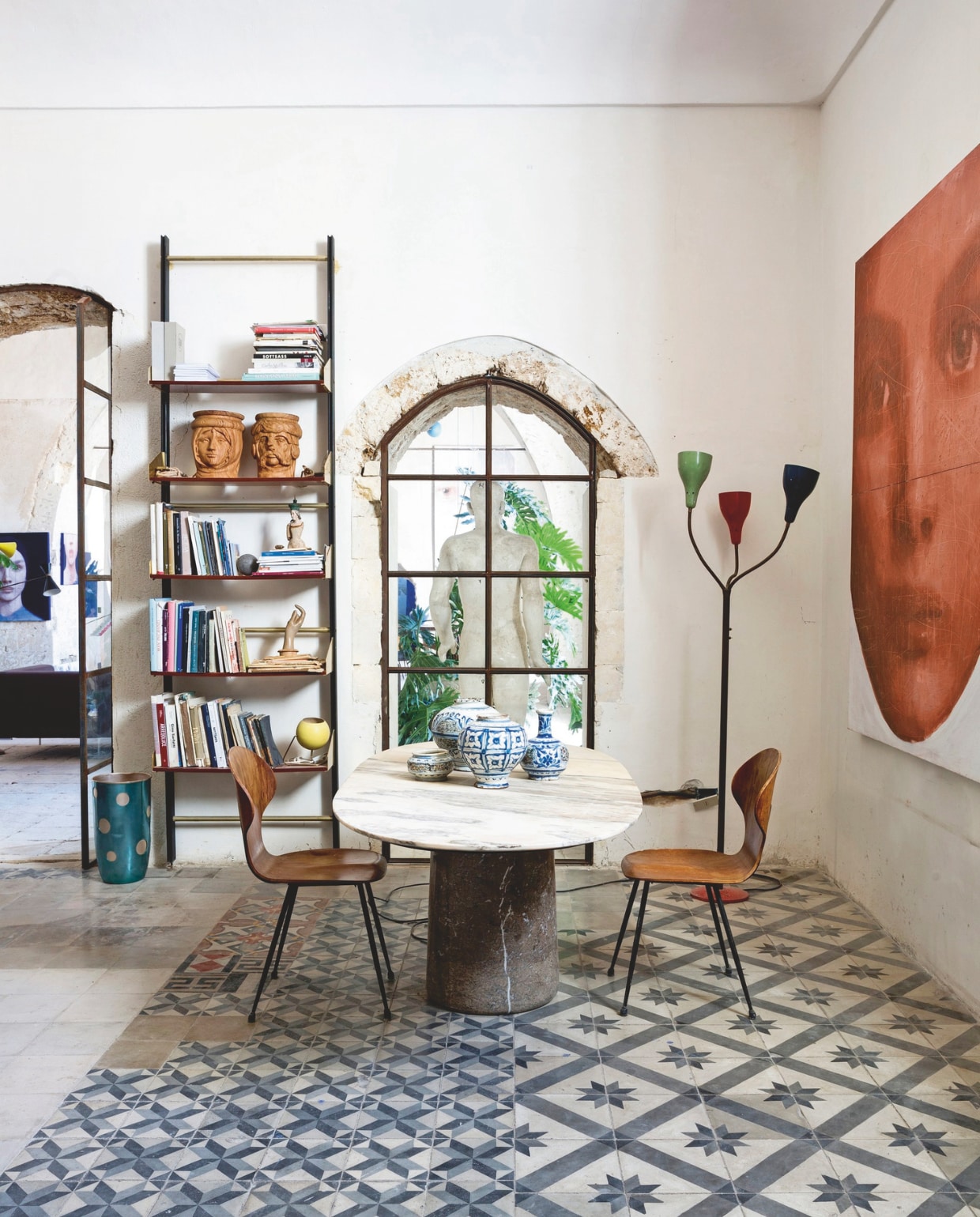 Naast het boekenrek uit de jaren 60 staat een paraplubak van Ettore Sottsass voor Rinnovel. Opnieuw twee Caltagirone-keramiek hoofden van Paolo Gagliardi uit Serio’s verzameling. Marmeren tafel van Angelo Mangiarotti, stoelen van Carlo Ratti. Op tafel antieke vazen uit de 18e eeuw. In de hoek een jaren 50-lamp van Oluce. Het schilderij Red Face is van Sergio Fiorentino. stijlvol wonen 07-2024 | fotografie en tekst Filippo Bamberghi/Living Inside