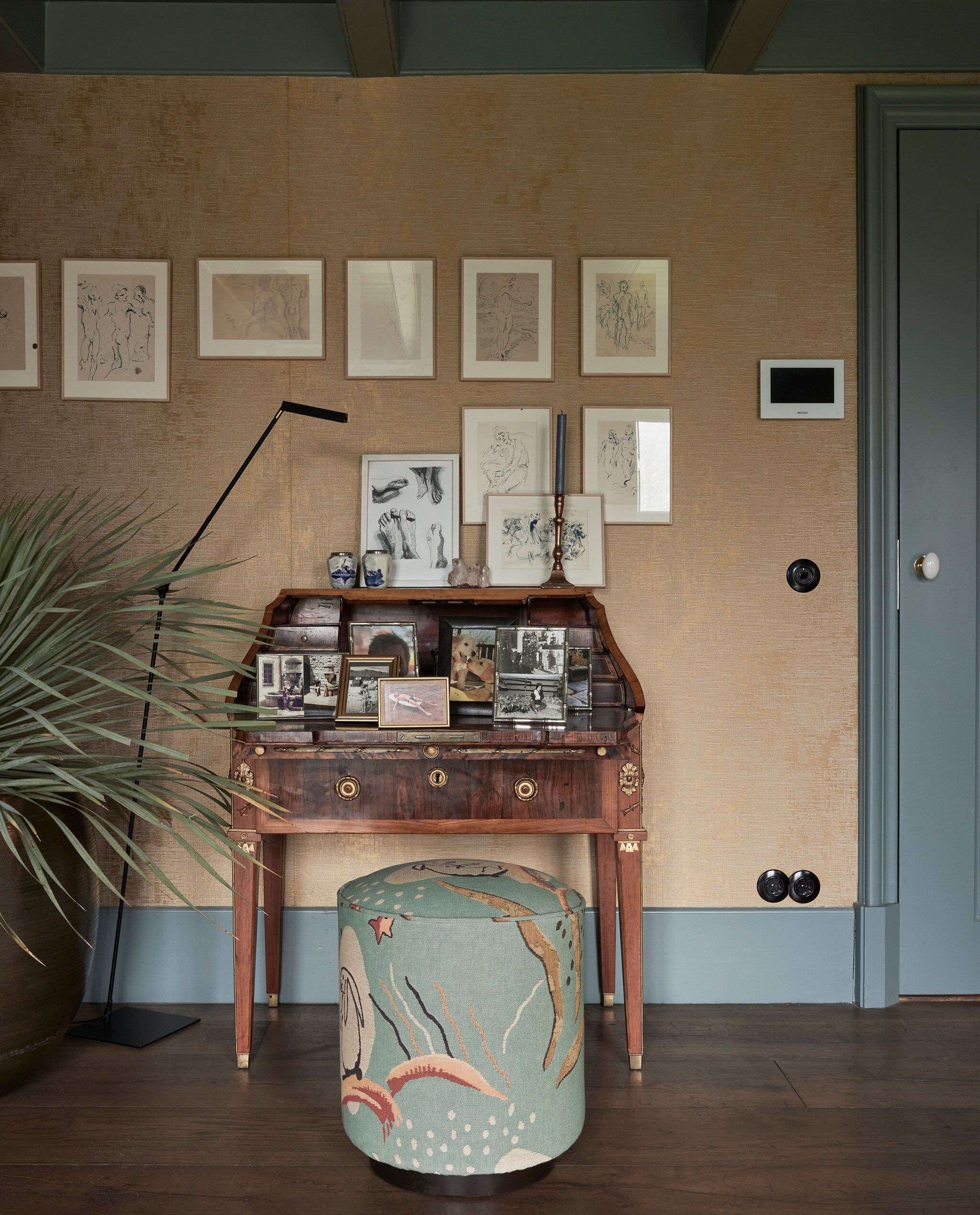 Goudkleurig behang collectie Monumenta van Nobilis. Bureau 18de-eeuws antiek Gustaaf III van Zweden. Lamp Zara. Poef Nobilis. Prenten Hans-Heinrich Focke. Houten vloerdelen van Landgoed Twickel. Stopcontacten moderne versie van Berker 1930. Kleur houtwerk Kerkgrijs licht 273 en Kerkgrijs Midden 129 Vettewinkel. vtwonen landelijk 01-2025 | Styling Marianne Luning | Fotografie Alexander van Berg | Tekst Merel van der Lande
