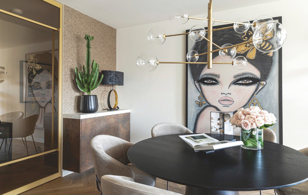 Op de kast van Bruynzeel staat een tafellamp van Eichholtz lamp. Het kunstwerk is van Wendy Buiter. De eettafel is van Table du Sud met stoelen en hanglamp van Eichholtz. stijlvol wonen 07-2024 | productie Taverne Agency | Styling Josephine Visser | Fotografie Chiela van Meerwijk
