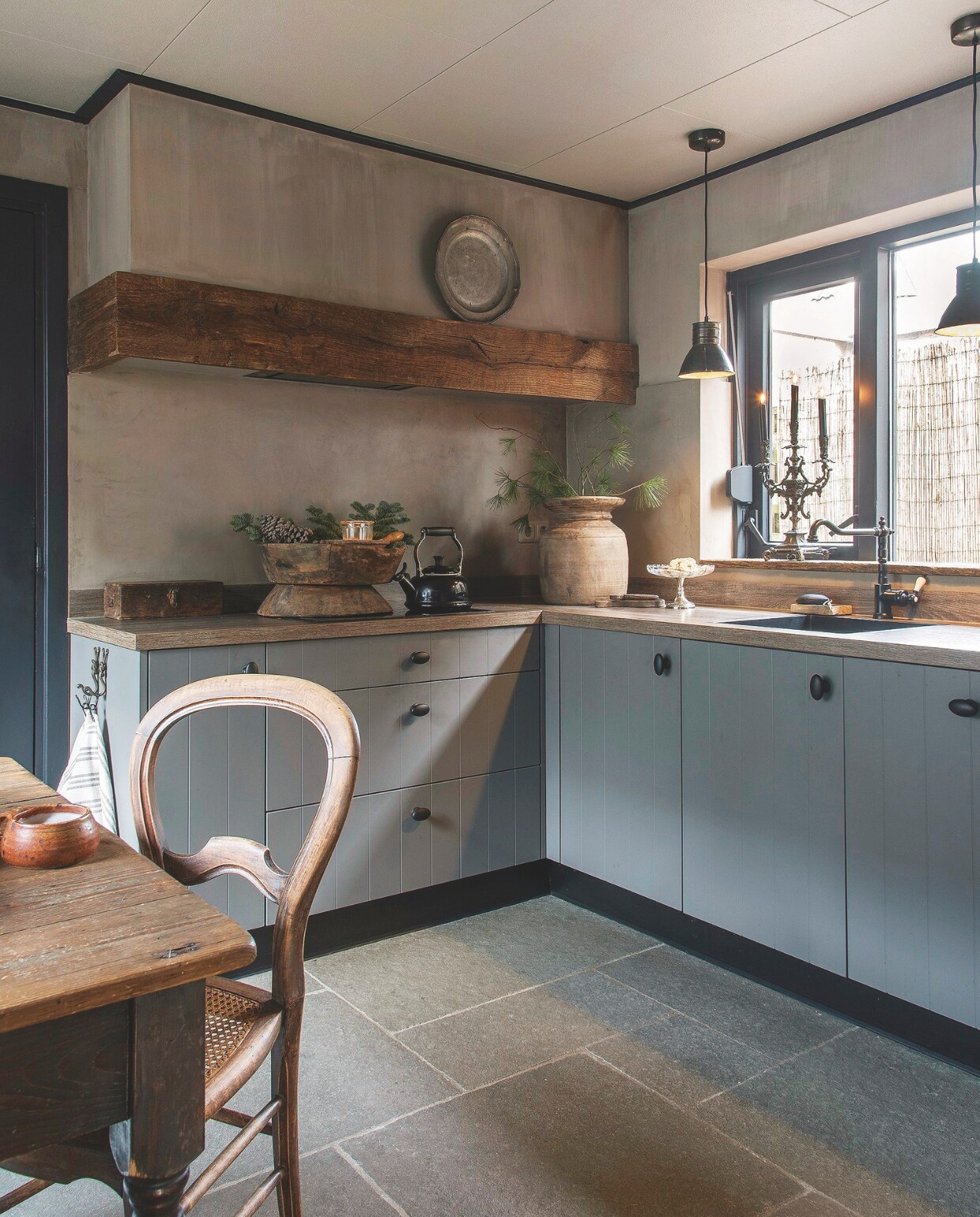 Om de afzuigkap stijlvol weg te werken, is er een zware, eiken balk omheen geplaatst. vtwonen landelijk 07-2024 | styling Peet! | fotografie Joyce Vloet