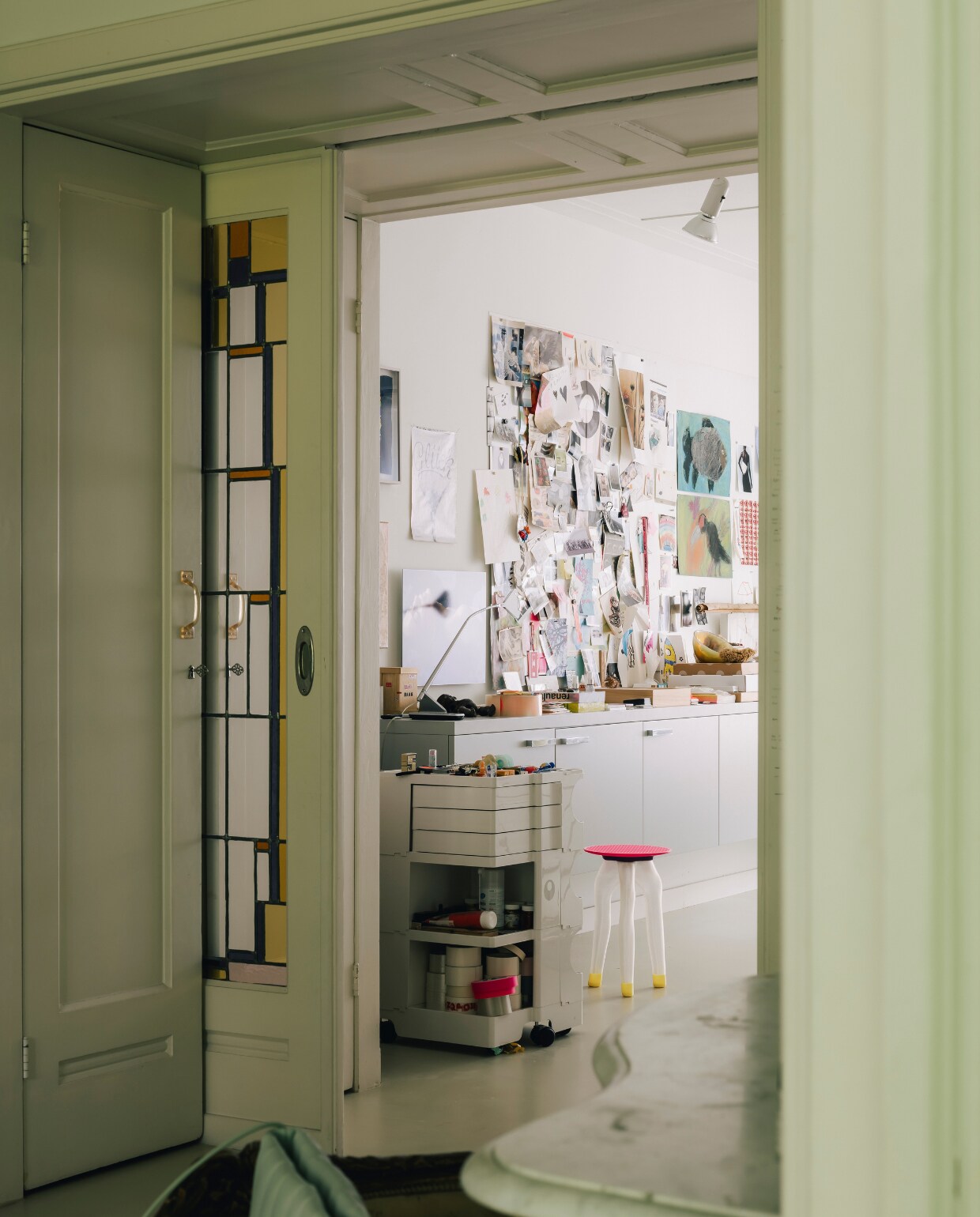 De originele glas-in-looddeur werd behouden en scheidt de slaapkamer van de werkkamer. Op de voorgrond staat tas Boulevard van Maeden. Het krukje is van Phygital Studio. stijlvol wonen 08-2024 | fotografie Katoo Peeters | tekst Tanne Donjacour Gielen