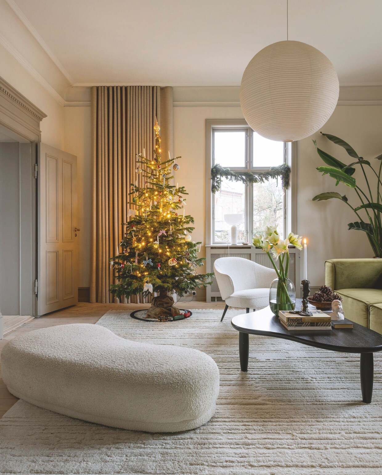 Poef Jotex, salontafel Mass Productions, bank en witte fauteuil Bo Concept, tapijt Rugvista, rijstpapieren lamp Hay. vtwonen 12-2024 | styling rikke graff juel | fotografie christina kayser onsgaard