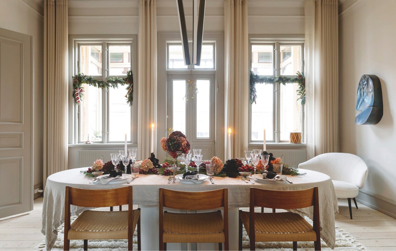 Linnen tafelkleed Nordal, zilveren borden Boho Habits, aardewerk Royal Copenhagen en rommelmarktvondsten, glaswerk vintage, servetten Broste Copenhagen, lamp Rubn, stoelen Pia van Poul Cadovius door DK3 Furniture, tapijt Jotex, stalen kunstwerk Kristian Jon Larsen. vtwonen 12-2024 | styling rikke graff juel | fotografie christina kayser onsgaard