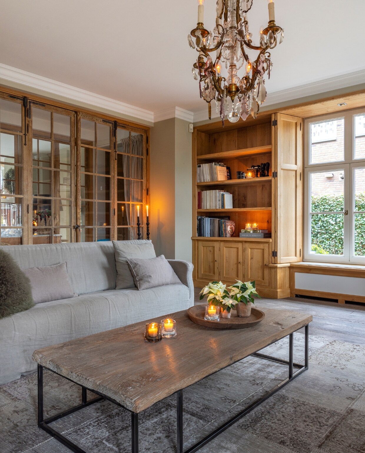 Antieke kristallen kroonluchter, oude eikenhouten deuren met ruitjes, tafel van een oude deur met een ijzerenonderstel, en houten vloer van’t Achterhuis. Het Vintage patchwork tapijt is van Perez Vloerkleden. De bank van Hoffz heeft een losselinnen bekleding. vtwonen landelijk 7-2024 | Fotografie Anneke Gambon
