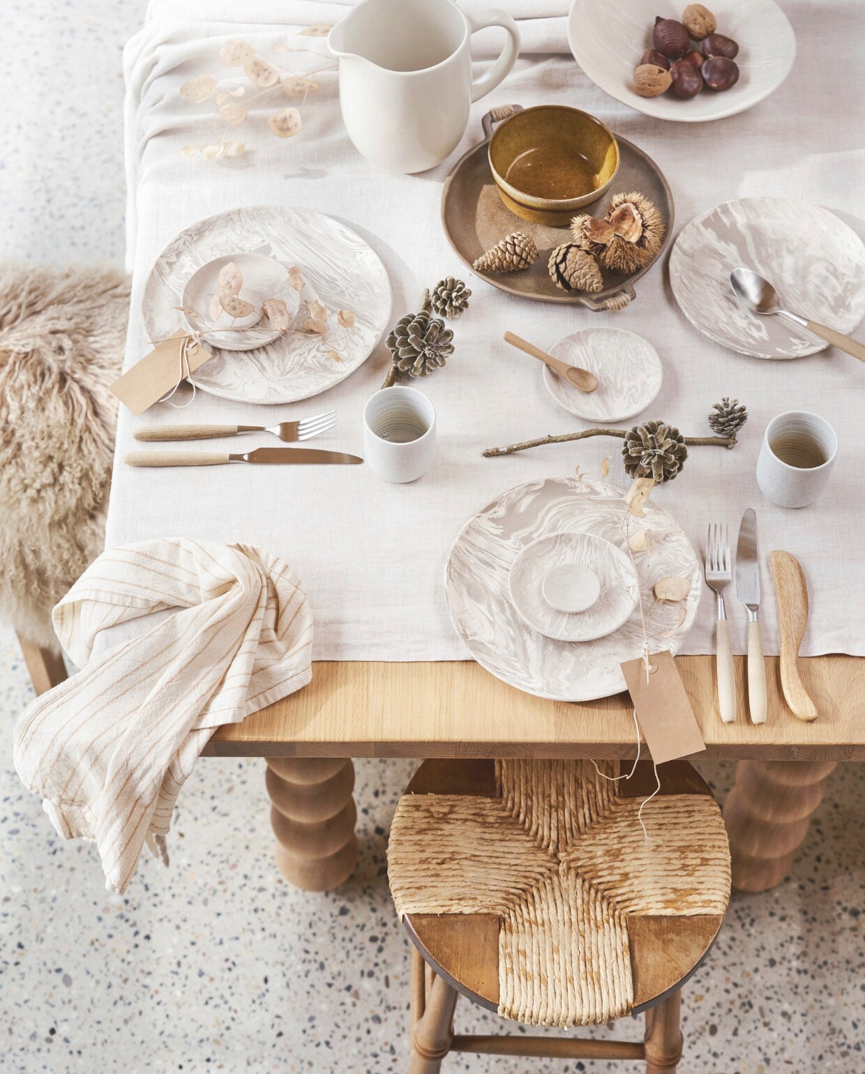 Eikenhouten eettafel Turn, 90x220 cm vanaf € 2139,- (studio-henk.nl). Greige schapenvacht € 149,95 en theedoek € 7,85 (iblaursen.nl). Gemarmerde  borden en schalen, prijs op aanvraag (@mettesophie.interiordesign). Kan Costa Nova &amp; Casafina € 31,03 (bol.com). Bestek met houten handvat Gent, vanaf € 6,95, bamboe lepel € 0,75, kraftpapieren labels, 20 stuks € 2,95 (dille-kamille.nl). Vintage houten kruk met touw, set van 2 € 375,- (bestwelhip.nl). Linnen tafellaken € 69,99 (zarahome.nl). Overig privébezit. vtwonen 13-2024 | styling Cleo Scheulderman | fotografie Jeroen van der Spek