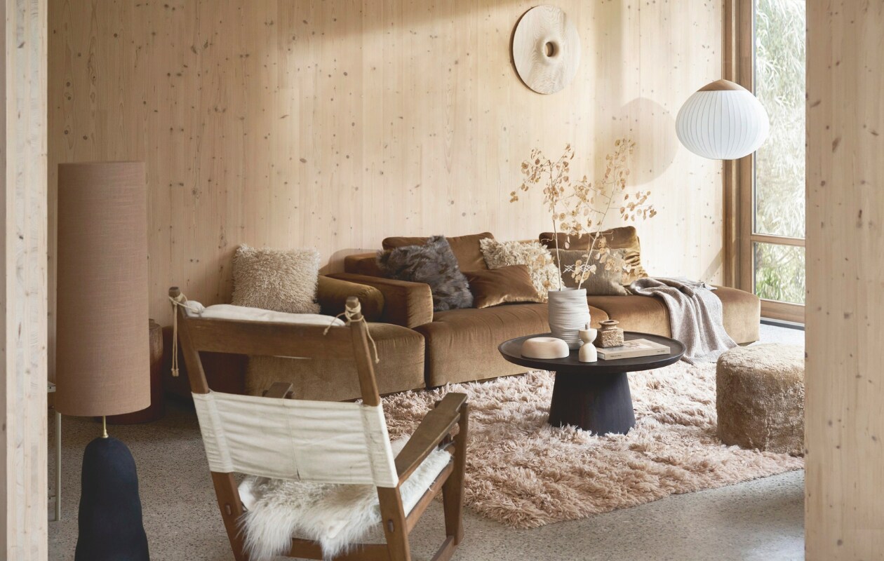 Elementenbank Develius, zoals afgebeeld 309x89x70 cm (bxdxh) vanaf € 4395,93 (andtradition.com). Vloerkleed Fluffy van HKliving, wol en katoen, 200x300 cm € 1695,-, mangohouten salontafel Coffee a gogo van vtwonen, 90x40 cm (Øxh) € 499,-, fluffy wollen kussen Meadow € 139,- (rechts) en keramische lampvoet Hebe € 399,- met linnen lampenkap Eclipse in sand € 189,- van Ferm Living en hanglamp Acorn van Bolia, fsc-gecertificeerd eiken en opaalglas, 64x55 cm (Øxh) € 1615,- (vtwonen.nl/shop). Vintage schommelstoel GE-673 van Hans Wegner voor Getama, 85x75x104 cm (bxdxh) € 2395,- (bestwelhip.nl). Houten object aan de wand en op tafel, prijs op aanvraag (rubenvdscheer.nl). Schapenvacht poef, 40x45 cm (Øxh) € 347,- en greige katoenen kussen (iblaursen.nl). Schapenvacht € 79,96 (vachtenspecialist.nl). Crèmekleurige fluffy kussenhoes € 29,99 (links), bruine fluffy kussenhoes € 22,99, ribgebreide plaid € 39,99 en keramische vaas € 39,99 (hm.com). Kleine vintage vaas € 30,- (studio-alloo.nl). Travertin kaarshouder € 49,95 (mooisa.com). Grenen wandpanelen maatwerk. Overig privébezit. vtwonen 13-2024 | styling Cleo Scheulderman | fotografie Jeroen van der Spek