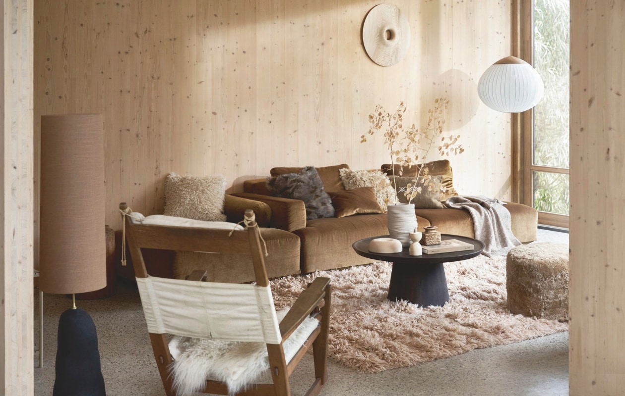 Elementenbank Develius, zoals afgebeeld 309x89x70 cm (bxdxh) vanaf € 4395,93 (andtradition.com). Vloerkleed Fluffy van HKliving, wol en katoen, 200x300 cm € 1695,-, mangohouten salontafel Coffee a gogo van vtwonen, 90x40 cm (Øxh) € 499,-, fluffy wollen kussen Meadow € 139,- (rechts) en keramische lampvoet Hebe € 399,- met linnen lampenkap Eclipse in sand € 189,- van Ferm Living en hanglamp Acorn van Bolia, fsc-gecertificeerd eiken en opaalglas, 64x55 cm (Øxh) € 1615,- (vtwonen.nl/shop). Vintage schommelstoel GE-673 van Hans Wegner voor Getama, 85x75x104 cm (bxdxh) € 2395,- (bestwelhip.nl). Houten object aan de wand en op tafel, prijs op aanvraag (rubenvdscheer.nl). Schapenvacht poef, 40x45 cm (Øxh) € 347,- en greige katoenen kussen (iblaursen.nl). Schapenvacht € 79,96 (vachtenspecialist.nl). Crèmekleurige fluffy kussenhoes € 29,99 (links), bruine fluffy kussenhoes € 22,99, ribgebreide plaid € 39,99 en keramische vaas € 39,99 (hm.com). Kleine vintage vaas € 30,- (studio-alloo.nl). Travertin kaarshouder € 49,95 (mooisa.com). Grenen wandpanelen maatwerk. Overig privébezit. vtwonen 13-2024 | styling Cleo Scheulderman | fotografie Jeroen van der Spek