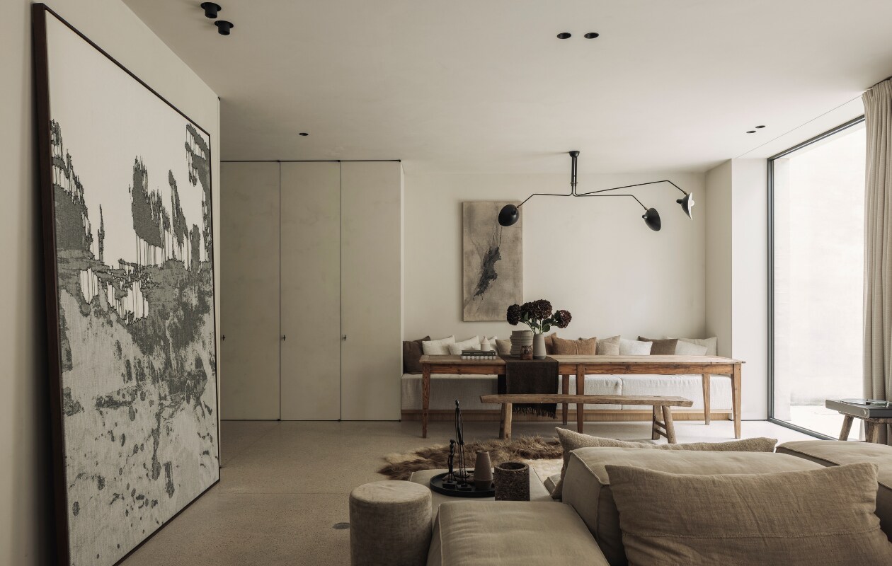 Eettafel van een vlooienmarkt in Barcelona. Lamp van Serge Mouille. Het kunstwerk aan de muur is van Eleanor Herbosch. Kunstwerk links Nathalie Van der Massen. De kast is maatwerk evenals de bank bij de eettafel. De houten bank komt van The Corner Studio. Loungebank en poef Extrasoft van Living Divani met kussens van Isabelle Yamamoto. Vacht van Carine Boxy. stijlvol wonen 01-2025 | fotografie Tijs Vervecken