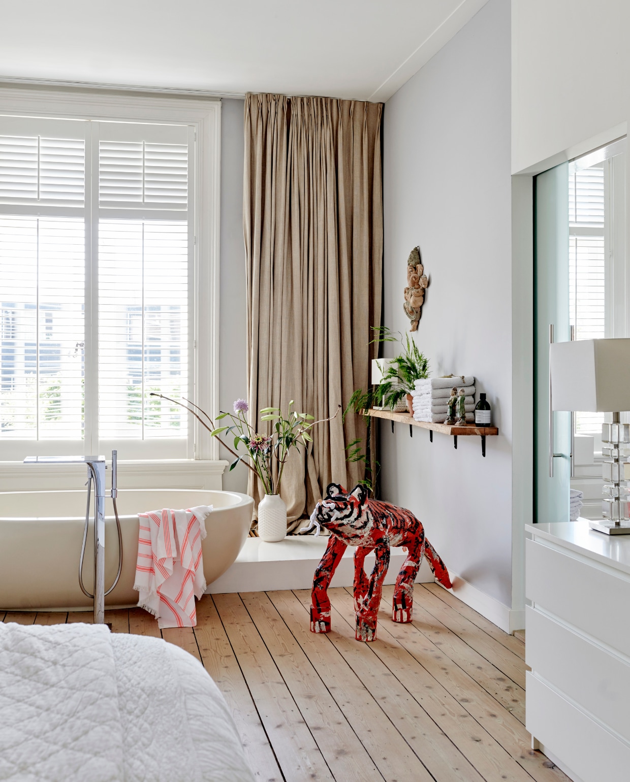 Het bad in de slaapkamer is zo bedacht door de vorige eigenaars. De vloer isgeschilderd met traplak waardoor hij tegen een stootje kan. De linnen gordijnen enshutters werden overgenomen van de vorige bewoners. De tijger van papier-machéis gemaakt door dochter Roos. Ladder van Atelier 8, kapstok en krukje Homestock.Hamamdoek Hema. vtwonen 04-2020 | productie Features &amp; More | styling Wilma Custers | fotografie Renee Frinking