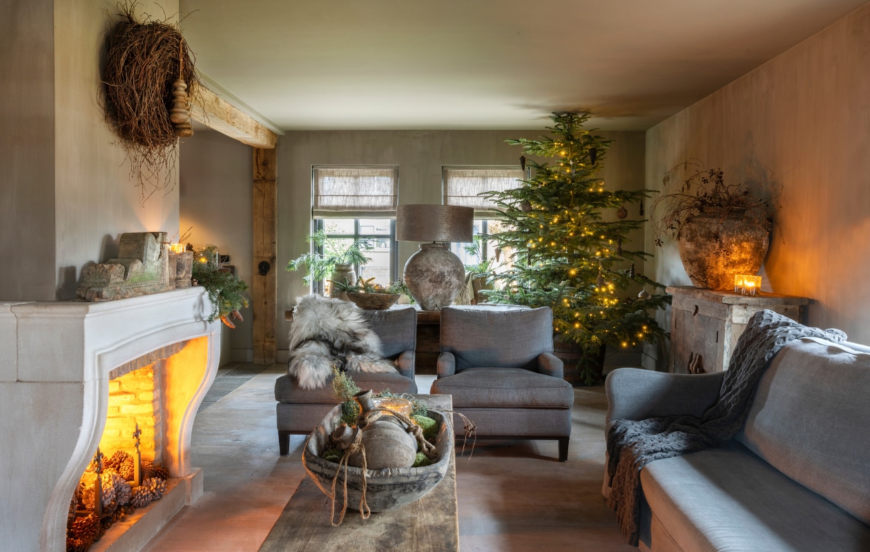 Bank en fauteuils van Mart Kleppe, tafel en de vouwgordijnen van Frieda Dorresteijn. Vachten en houten trog op tafel van Bibi’s Lifestyle, windlichten van Puur Groen. De grijze plaid en de kussens op de bank zijn van Silt. Alle wanden en plafonds zijn geverfd in kleur Gritti van Carte Colori, geleverd door René Houtman. vtwonen landelijk 07-2024 | Fotografie Anneke Gambon