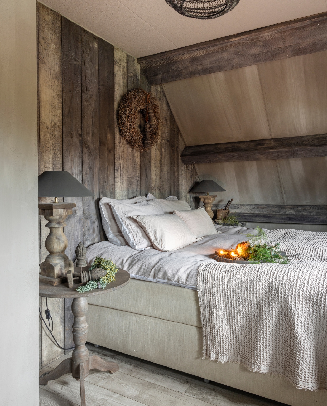 Bed van Swiss Sense. Plaid, dekbedovertre en kussens van Passion for Linnen. Diana kocht de lampen bij Rivièra Maison. De krans en de klossen komen van Bibi’s Lifestyle. Diana en Rene maakten de achterwand zelf,  van oude steigerplanken die zijn behandeld met loogbeits van Esatto. vtwonen landelijk 07-2024 | fotografie Anneke Gambon