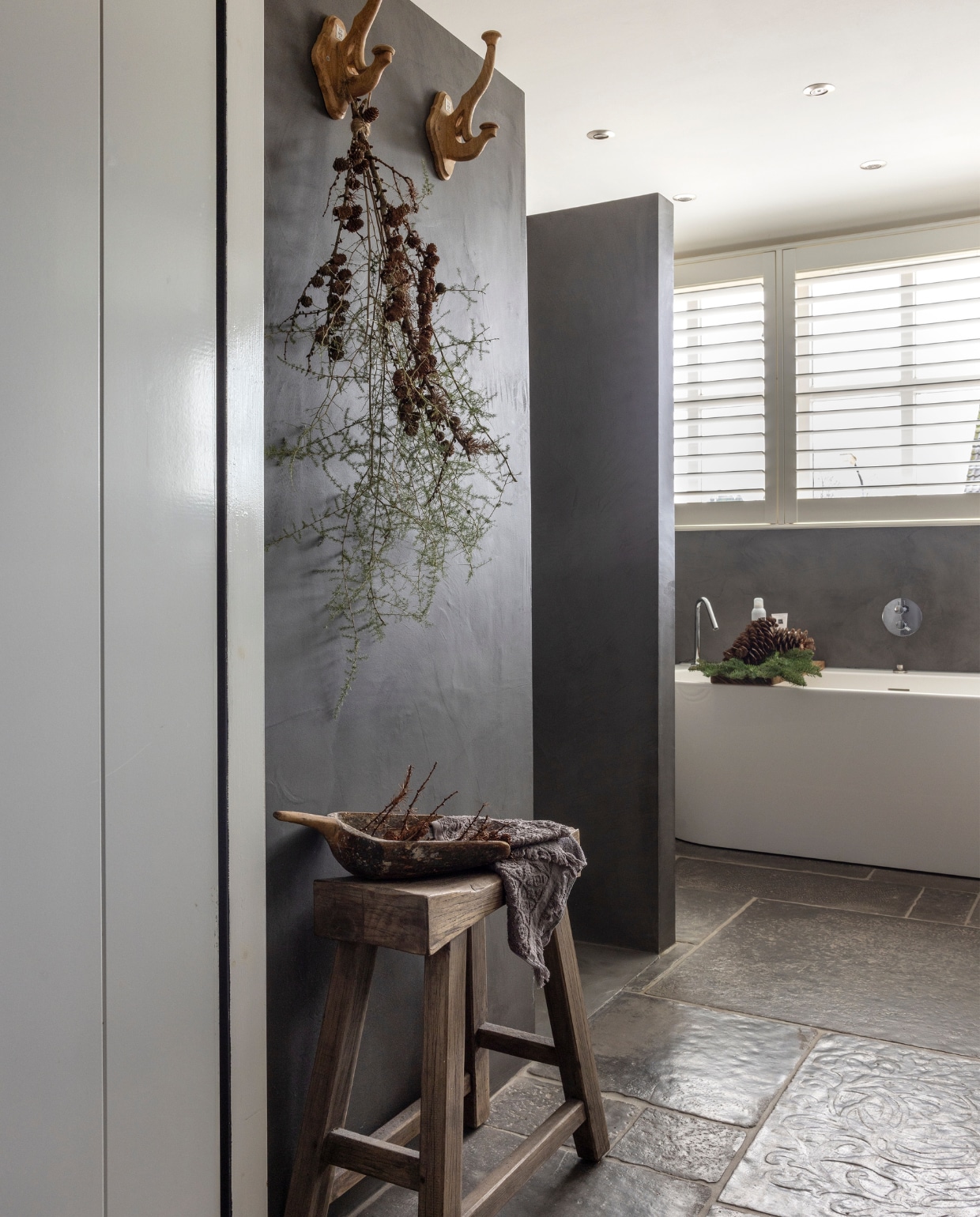 Ook in de badkamer liggen Castle Stones in de kleur Old Grey. De wanden zijn afgewerkt met Mortex van Beal. Shutters van Jasno. vtwonen landelijk 07-2024 | fotografie Anneke Gambon