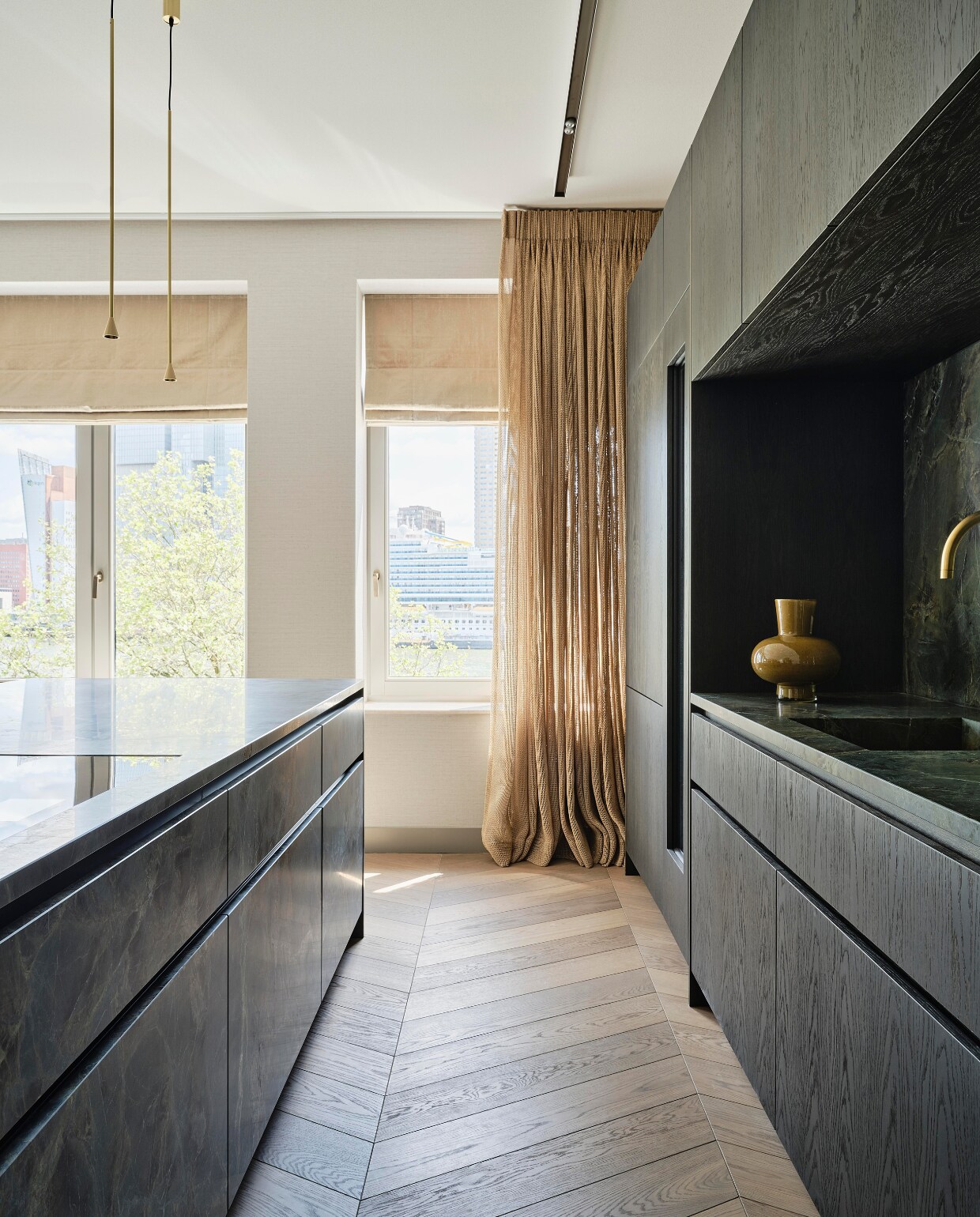 Linda: ‘Voor de keuken gebruikte ik donkere houten kasten. Dat kan hier omdat de ruimte zelf heel licht is. De keuken moest een blikvanger worden. Daarom liet ik door een steenhouwer een keukeneiland maken uit een blok kwartsiet. Het is een ideale plek om samen te koken en vrienden te ontvangen.’ Krukken Verpan, hanglampen Trizo21. stijlvol wonen 08-2024 | Fotografie Space Content Studio