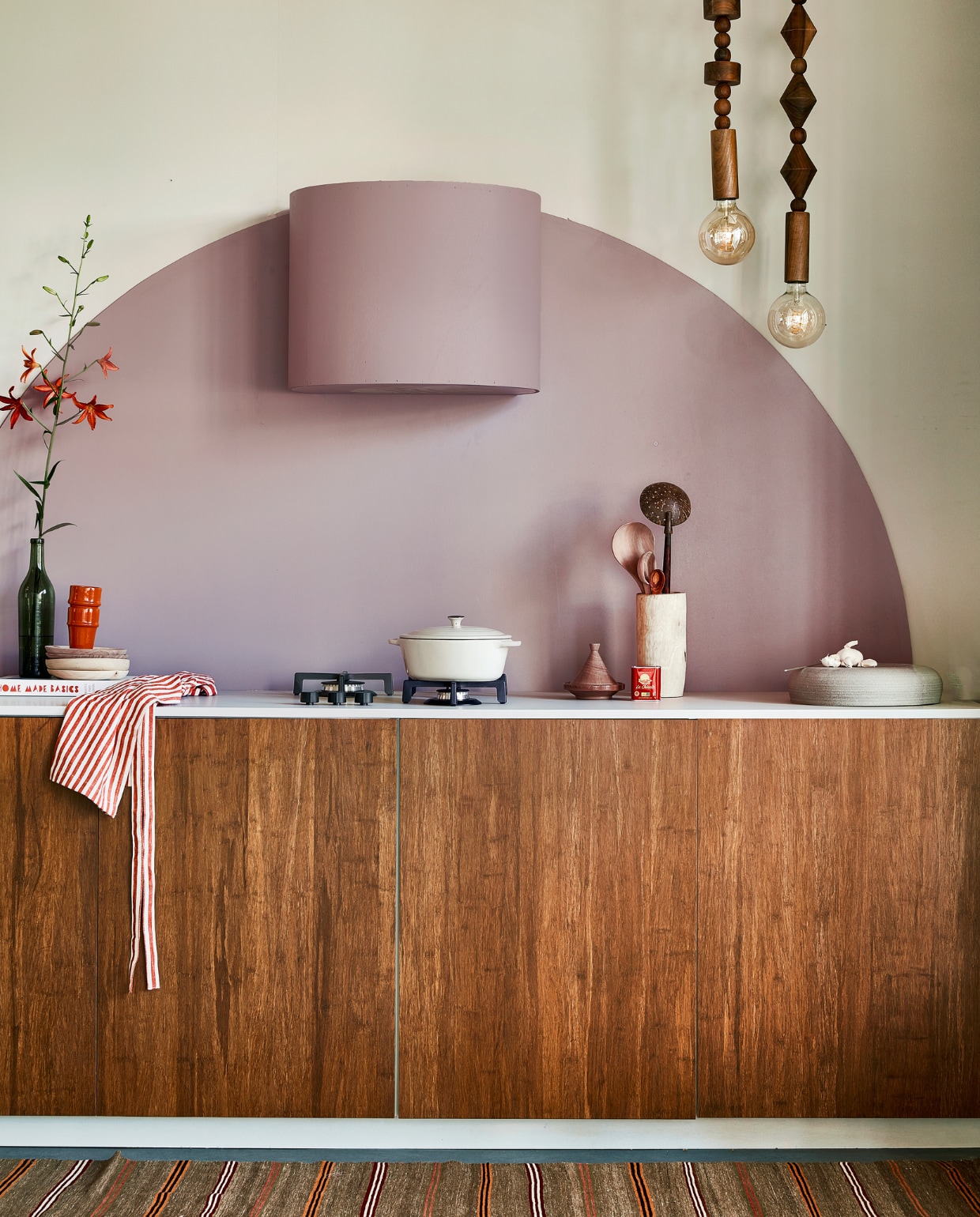 Muurverf Flexa Easycare Keuken kleur Cosmic Glory, ronde vorm en bekleding afzuigkap kleur Heart Wood, per liter € 25,49 (flexa.nl). Bamboe fronten Destiny Caramel, 60x80 cm (bxh) € 259,-, aanrechtblad prijs op aanvraag (frontz.nl). Vloerkleed vintage, 215x86 cm € 350,- (rozenkelim.nl). Groene fles € 7,50 (kringloop). Kookboek Home Made Basics van Yvette van Boven € 34,99 (bol.com). Kralenlampen, per stuk € 659,-, rode mokken € 9,95, houten borden € 21,-, pollepels vanaf € 9,95, houten vijzel € 36,-, kleine tajine € 8,50 (householdhardware.nl). Schort € 9,99 (hm.com). Aardewerken pan € 39,99 (zarahome.com). Handgemaakte turnaround dish € 185,- (lilokeramiek.nl). vtwonen 09-2022 | styling Leonie Mooren | fotografie Peggy Janssen