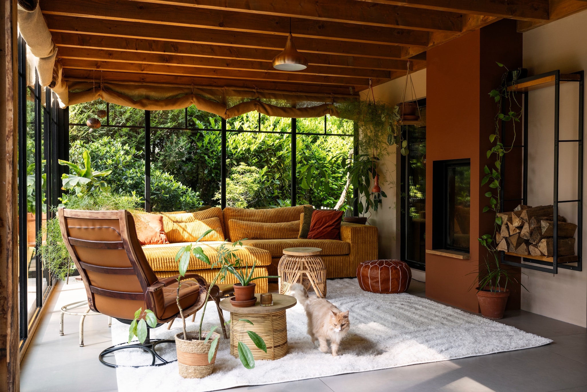 Wandkleur Transcend van Histor, wandkleur schouw Histor ppg16-23 Tampico Brown. Vloerkleed Lova Arches Creme van Volero, vintage draaifauteuil gekregen van een vriendin, rieten bloempot Action, voorste tafeltje omgekeerde plantenbak van Bloomingville met zelfgemaakt houten blad, achterste rotan tafeltje Big Bazar met zelfgemaakt houten blad van oud steigerhout. Marokkaanse poef The Souks, bank Hulk van PureWonen, verticale haard Bodart &amp; Gonay Concept Green 540 Dfv. vtwonen 02-2025 | styling Ilona Jongepier | fotografie Dana van Leeuwen | tekst Chris Muyres
