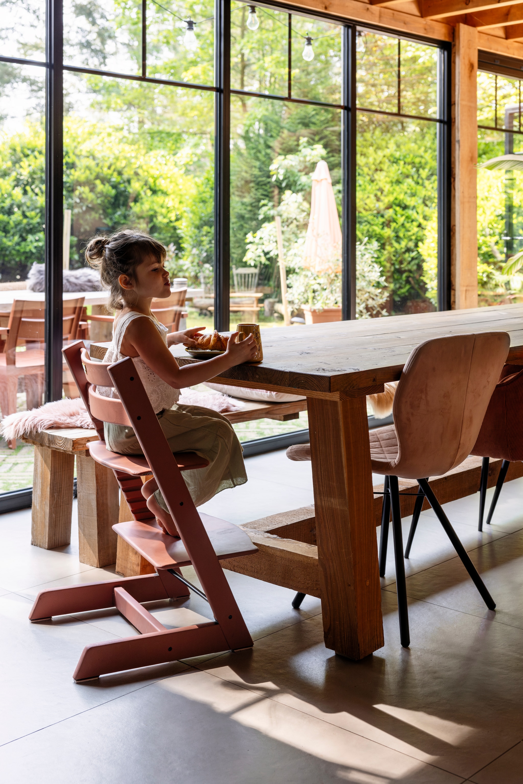 Tafels en bank op maat gemaakt door een timmerman via Marktplaats, kleed op de bank Temu, mok en bord Folor, stoelen Kwantum, Tripp Trapp stoel van Stokke, lichtsnoer Action, buitenstoelen Kwantum. vtwonen 02-2025 | styling Ilona Jongepier | fotografie Dana van Leeuwen | tekst Chris Muyres