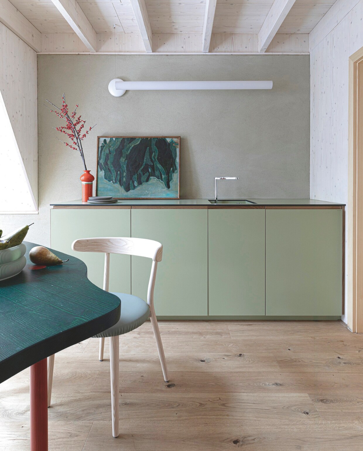 Keuken op maat gemaakt door Alta Cucine. Tafel Studio Beltrame, stoel Bio van Balutto Associati voor Livoni, wandlamp Tu-O van Linea Light, fruitschaal Sheyn, oranje vaas vintage, schilderij Eugenio Sguazzotti. vtwonen 13-2024 | productie Living Inside | fotografie Monica Spezia