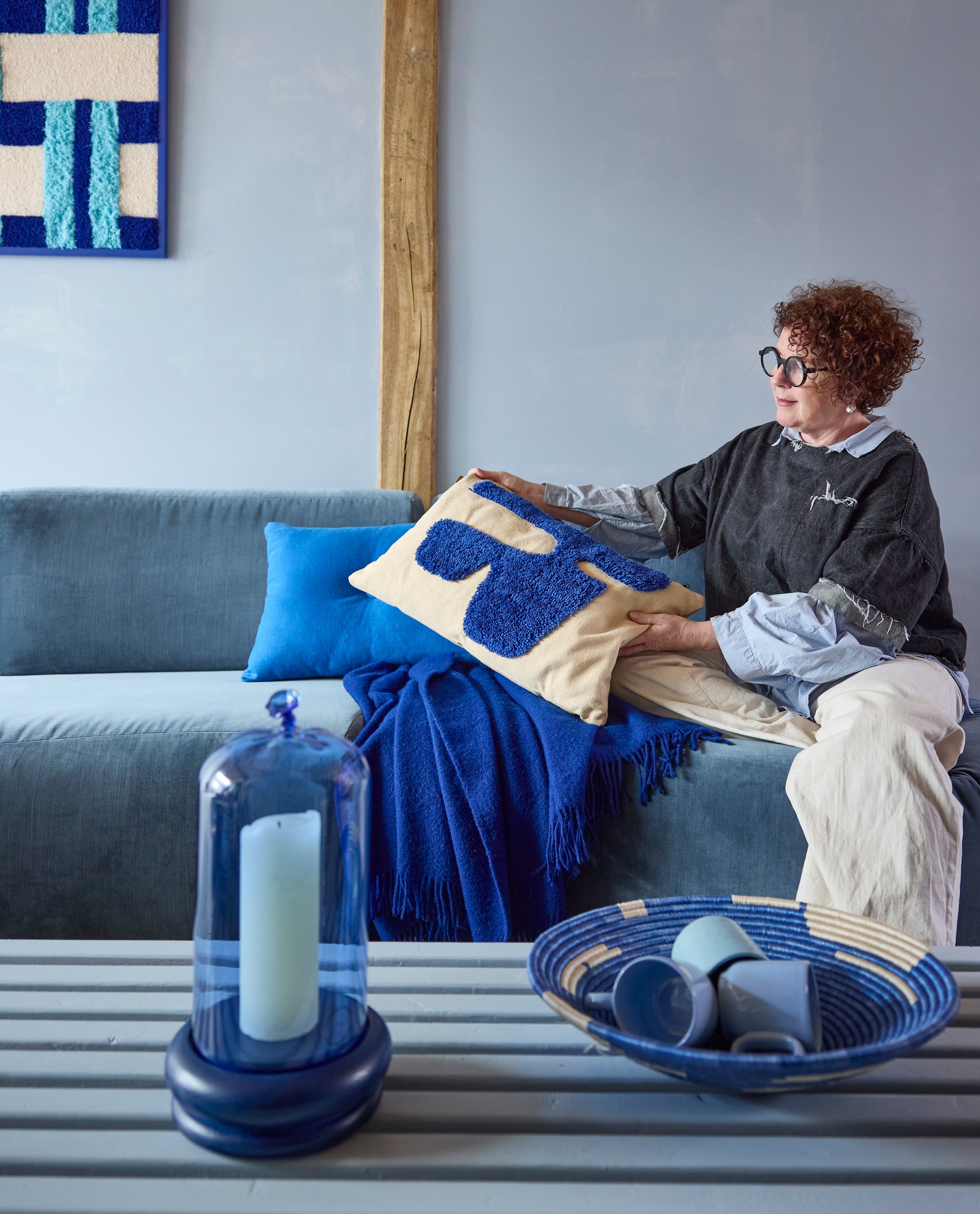 Kalkverf Blue Bay, 1 liter € 66,- (vestingh.nl). Modulaire bank Benson, 241x114x83 cm (bxdxh) € 4975,- (rapture.amsterdam). Houten salontafel, 212x65x27 cm (lxbxh) prijs op aanvraag (com-anders.nl). Getuft wandkleed in met de hand gemaakte houten lijst, 21x90 cm € 835,- (steffievandenelshout.nl). Lamswollen plaid Boston, 130x200 cm € 131,95 (aabe.nl). Blauw fluwelen kussen Dot van Hay € 95,- en kussen Lay van Ferm Living, katoenen canvas met getufte wol € 79,- (loods5.nl). Stolp Balloon, borosilicaatglas en essenhout € 160,- (polspotten.com). Sisal schaal Shoreline van Maison Suku, vanaf € 34,95 (shop.vtwonen.nl). Keramische mokken Jose, per stuk € 18,94 (nordal.com). vtwonen 4-2025 | styling Marianne Luning | fotografie Alexander van Berge