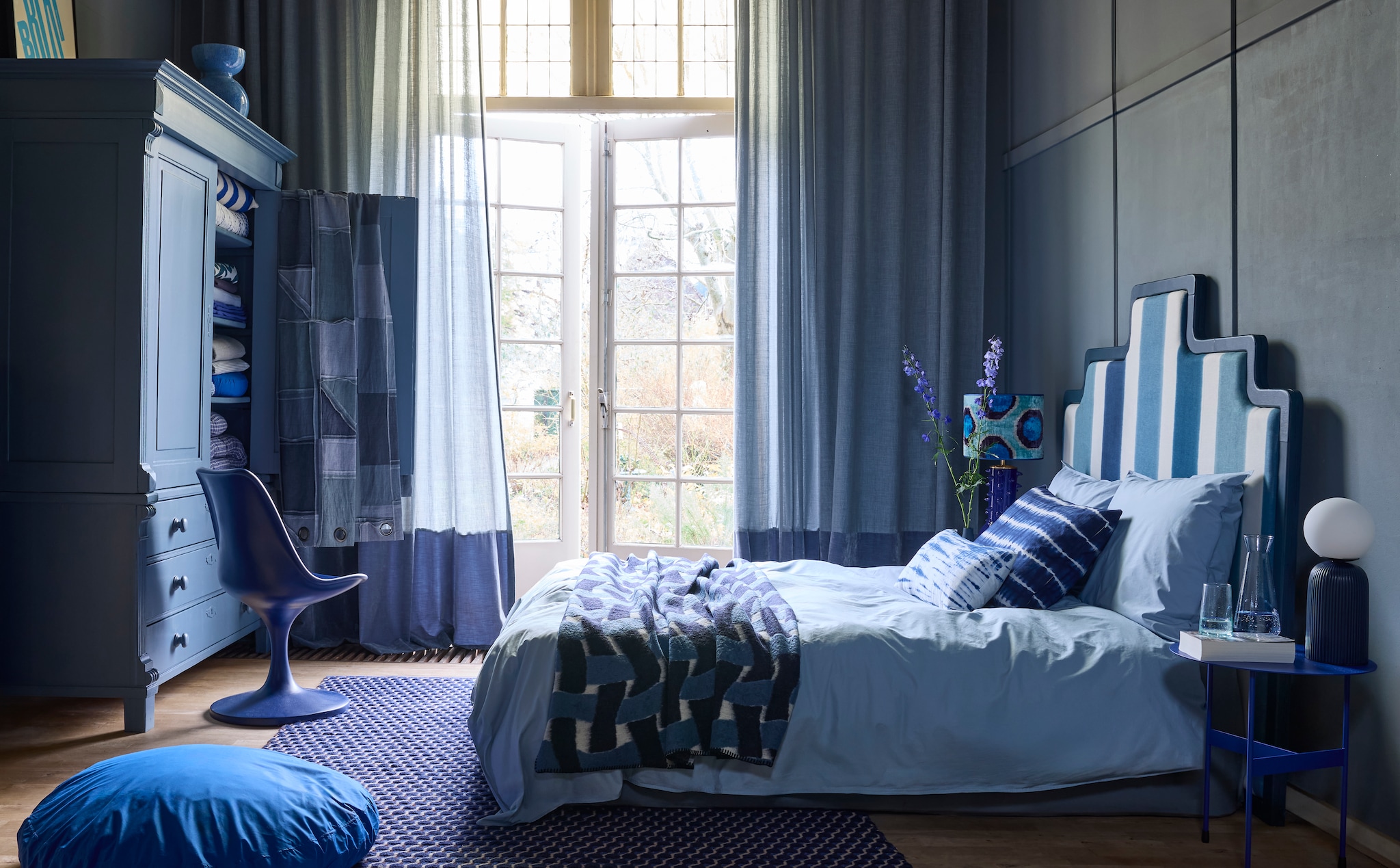 Krijtverf Blue Stone, 1 liter € 51,45 (pure-original.com). Houten kast, maatwerk, prijs op aanvraag (com-anders.nl). Patchwork stof Reclaim Reversible Denim van Kirkby Design, katoen en linnen, 140 cm, per meter € 254,50 (romo.com). Keramische vaas Bol vanaf € 40,- (polspotten.com). Gordijnstof Tick-Tock Crushed Reboot van Chivasso, linnen en polyester, 300 cm (h) per meter € 147,50 met gordijnstof Sensual Velvet van Chivasso, polyester en katoen, 140 cm (b)per meter € 105,- (jab.de). Vloerkleed Channel, wol en katoen, 170x240 cm € 779,- (hay.com). Hoofdbord maatwerk, prijs op aanvraag (com-anders.nl) met linnen stof Mirmande Indigo van Designers Guild, 140 cm, per meter € 119,-(wva.nl). Plaid Pool Throw Recycled Marine van Kirkby Design, gerecycled wol en polyester, 140x230 cm € 407,- (romo.com). Biologisch percale katoenen dekbedovertrek Sky Blue, vanaf 140x200 cm € 94,95 en donzen zitkussen Really bigdot met biologisch percale katoenen kussensloop bigdot € 59,95 (suite702.com). Polyester stoel Tulip van Household Hardware, 49x45x83 cm (bxdxh) € 495,-, kussens Tie-Dye van vtwonen € 34,95, stalen bijzettafel Mira Low van Spinder Design, 40x45 cm (Øxh) € 129,-, tafellamp Dash van Zuiver, keramiek en opaalglas € 149,-, glazen karaf Claude van Brût Homeware € 34,50, drinkglas Coneshaped van Household Hardware € 4,25, tafellamp met kap Madame Garage, prijs op aanvraag, andere modellen in de vtwonen shop (shop.vtwonen.nl). Alexander van Berge