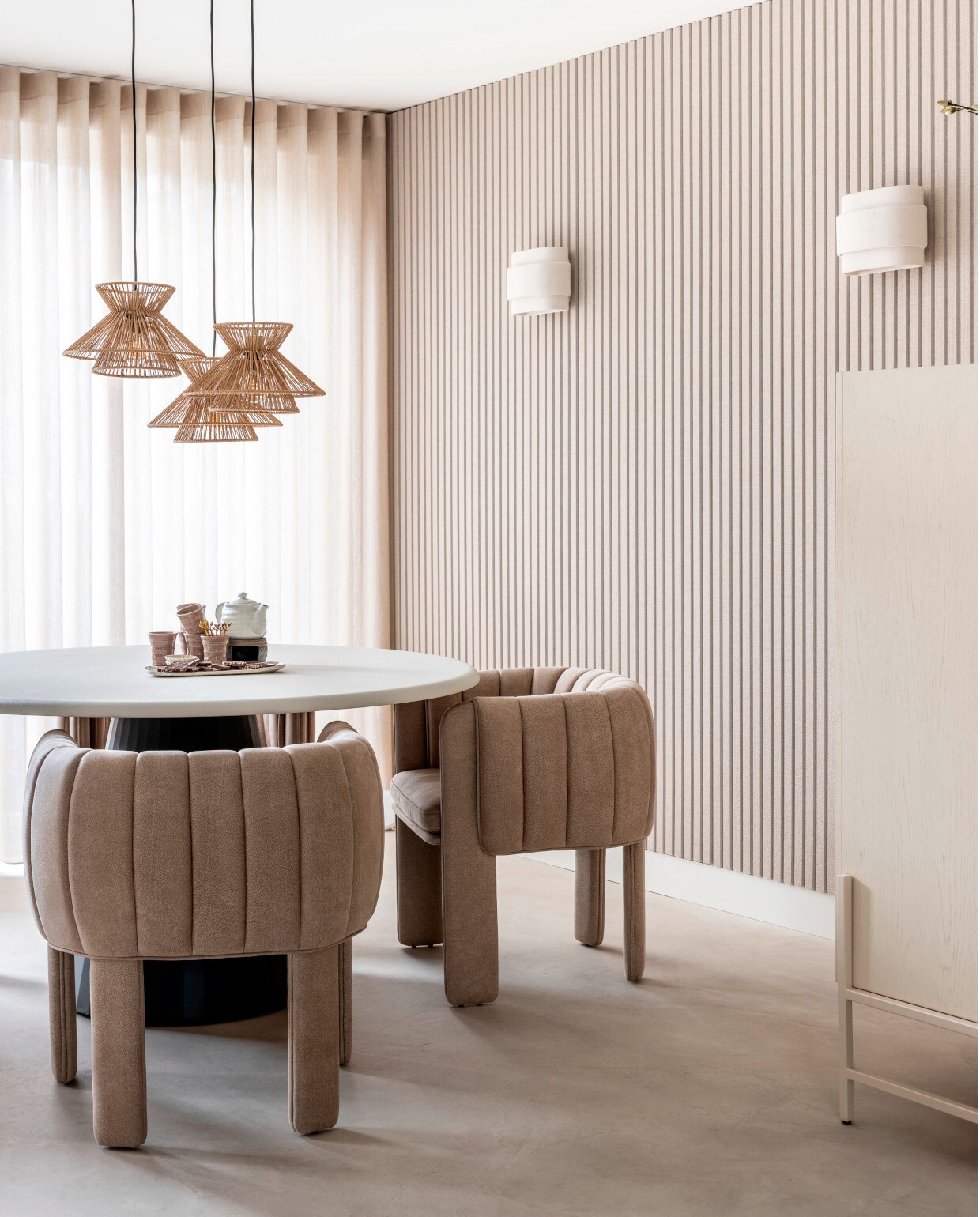 Muurverf Grand Lady van Flexa Creations, vinylvloer met pvc-toplaag Supreme 40 beton ciré lichtgrijs 5965 van Aanhuis.nl, linnen gordijnen Weekend van Vadain in kh 14 natural transparant van Aanhuis.nl, akoestische wand met behang van GewoonGers, eettafel Lund in Stone Skin en onderstel in Off Black, 140 cm (Ø) via Eijerkamp,beige eetkamerstoelen Liselore via Eijerkamp, opbergkast Faces, eikenhout fineer, 100x45x140 cm (bxdxh) via Eijerkamp, hanglamp Tasman van Lucide via vtwonen, beige wandlamp Louis - Anita Le Grelle van Serax, 19 cm (h) via vtwonen, serveerschaal Koto van Mywabi, smalle koffiekoppen Kop Wa van Mywabi, theeverwarmer Ganbatte van Mywabi, theepot Fukamushicha van Mywabi,theelepels Atsu Deba van Mywabi en sojaschaaltjes Nakano van Mywabi. vtwonen 02-2025 Dossier Stof verf behang | styling Eva van de Ven | fotografie Margriet Hoekstra