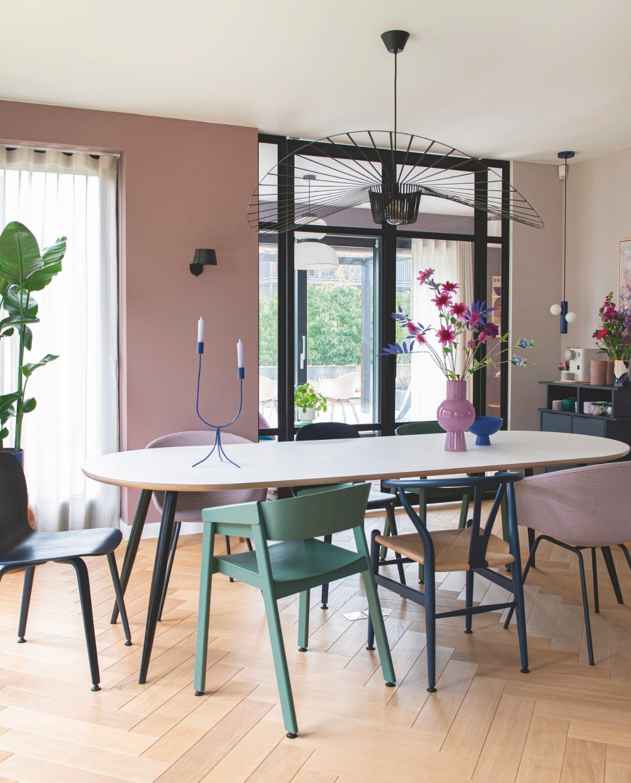 Tafel Tables by Tim. Groene stoel en stoel links Muuto. Blauwe stoel Carl Hansen &amp; Søn. Roze stoelen Hay. Kandelaar K’willeminhuis. Roze vaas Mica Decorations. Blauw schaaltje Raawii. Hanglamp tafel Petite Friture. Muurlamp Tonone. Koffiedressoir Tylko. Vaas Marinski Heartmades. Kopjes Bunzlau Castle, Urban Nature Culture, &amp;klevering. Hanglamp witte bollen Fést. Muurverf Sulking Room Pink en Peignoir van Farrow &amp; Ball. Gordijn De Ploeg. Urban Wood Le Havre visgraat van Martijn de Wit Vloeren. vtwonen binnenkijkspecial 11-2024 | styling Jeske Weel | fotografie Caroline Coehorst