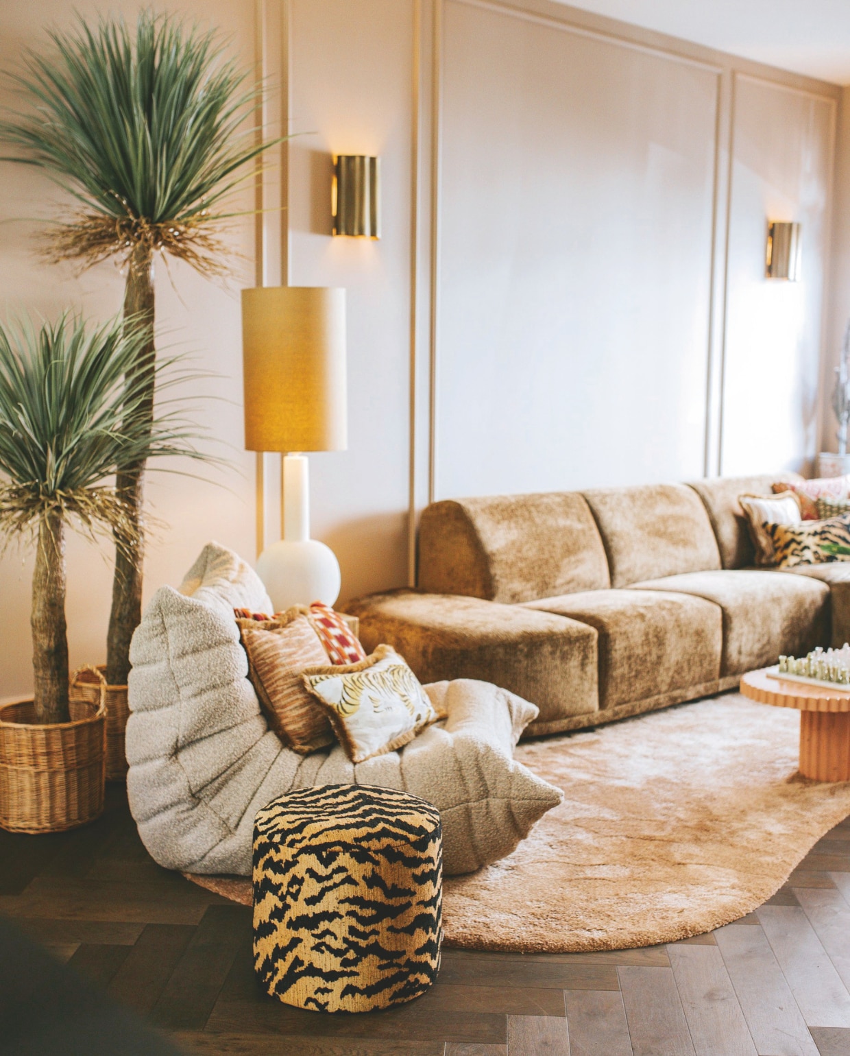 Bank Zitmaxx Wonen, plantenmanden Dille &amp; Kamille, wandlampen Fringe van vtwonen, stoel Togo vintage via Tgndraeds, kleed zelfontworpen via Nordik, salontafel Masoe Studio, muurkleur Roman Plaster van Little Greene, behang Raffia Madagascar van Elitis, vloer Cibo Vloeren, staande lamp Urban Nature Culture, kussens en poef Sophie Dirven Design. vtwonen binnenkijkspecial 11-2024 | fotografie Merel Visscher