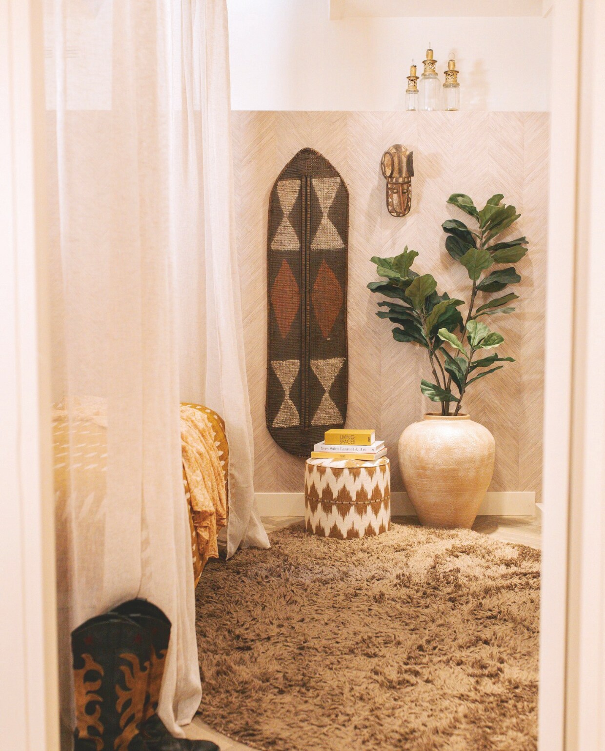 Vloerkleed Wehkamp, laarzen Paul Warmer, behang Cohiba van Arte, muurkleur RAL 9010, bedhemel Loberon, dekbedovertrek Ikat van vtwonen, poef Sophie Dirven Design, pot Urban Nature Culture, Afrikaans schild en masker vintage. Overig onbekend. vtwonen binnenkijkspecial 11-2024 | fotografie Merel Visscher