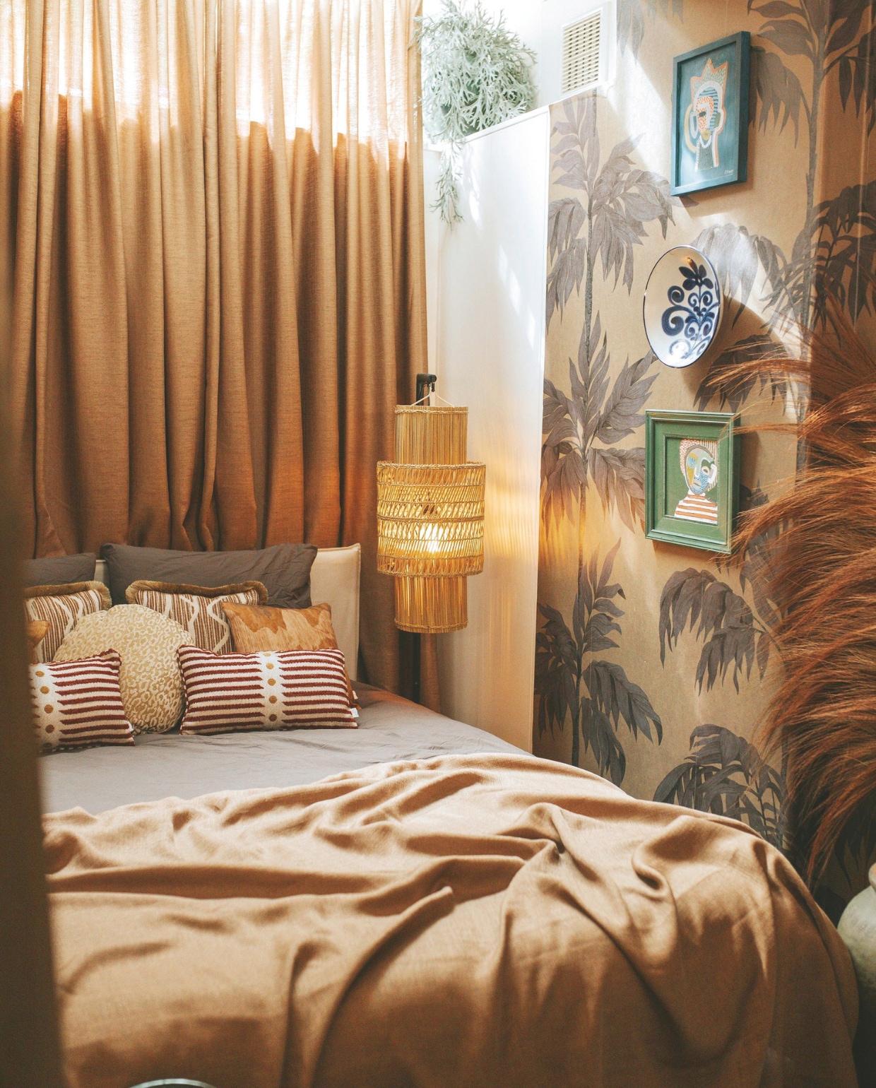 Behang Vintage Palm Tree van Belarte Studio, gordijnen Inbetween Chai Copper van Veneta, lamp Marktplaats, bed Ikea, sprei zelfgemaakt van oud gordijn, sierkussens Sophie Dirven Design, schilderijen zelfgemaakt, schaal aan wand kringloop. vtwonen binnenkijkspecial 11-2024 | fotografie Merel Visscher