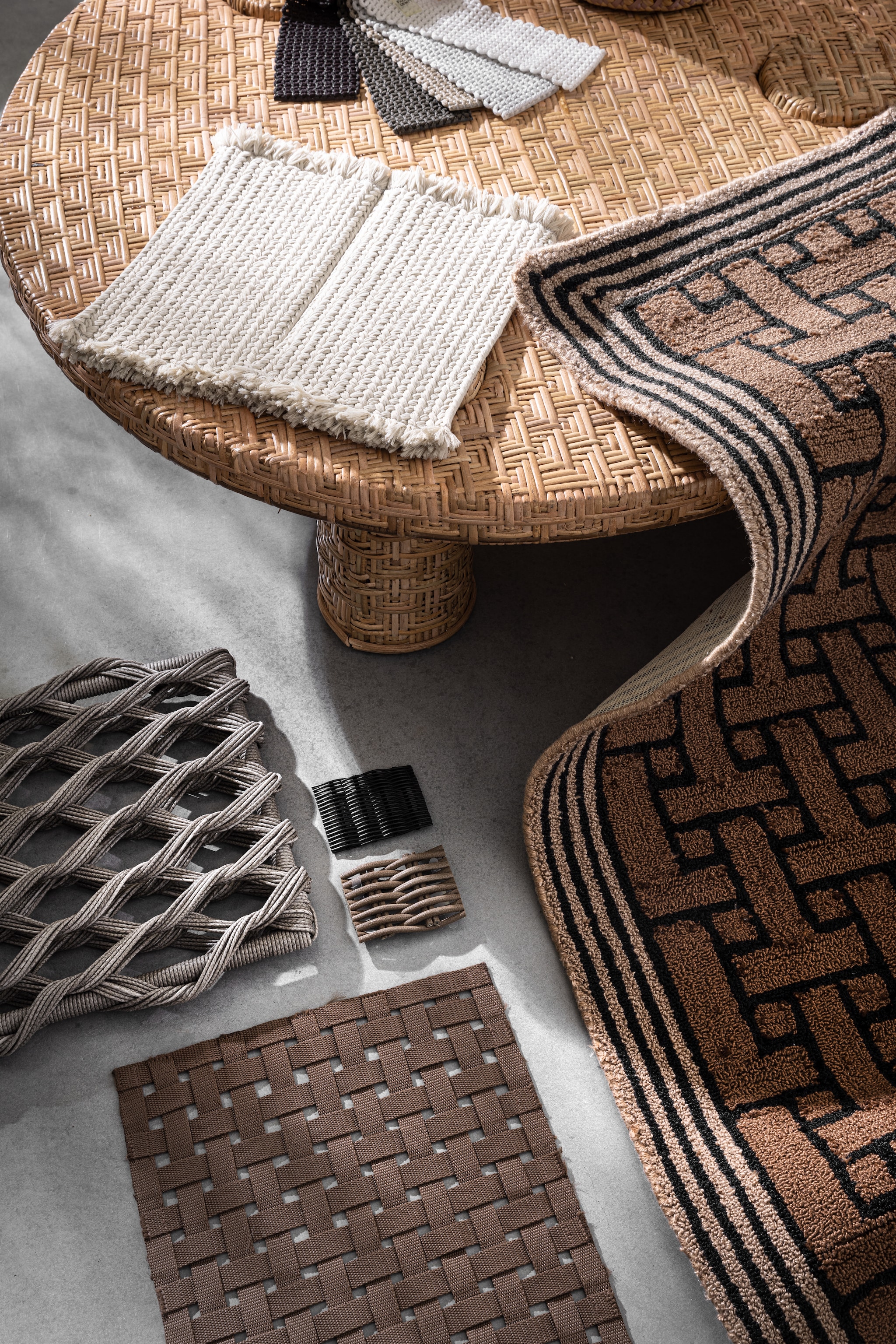 Vloerkleed T Monogram outdoor van Ted Bakerin Light Brown, gerecycled pet, 140x200 cm € 299,-(vloerkledenwinkel.nl). Rotan salontafel, 101x32,5 (Øxh) € 595,- (hkliving.com). Tapijtstaal met kwastjes Sahara van Paola Lenti in S01, polyolefin, acrylvezel en polyurethaan, gevlochten stofstalen Aero van Paola Lenti, grote gevlochten stalen in grijs en bruin en kleine gevlochten stalen van Paola Lenti in zwart en bruin (dacks.nl). vtwonen 02-2025 | styling marlies does | fotografie peggy janssen