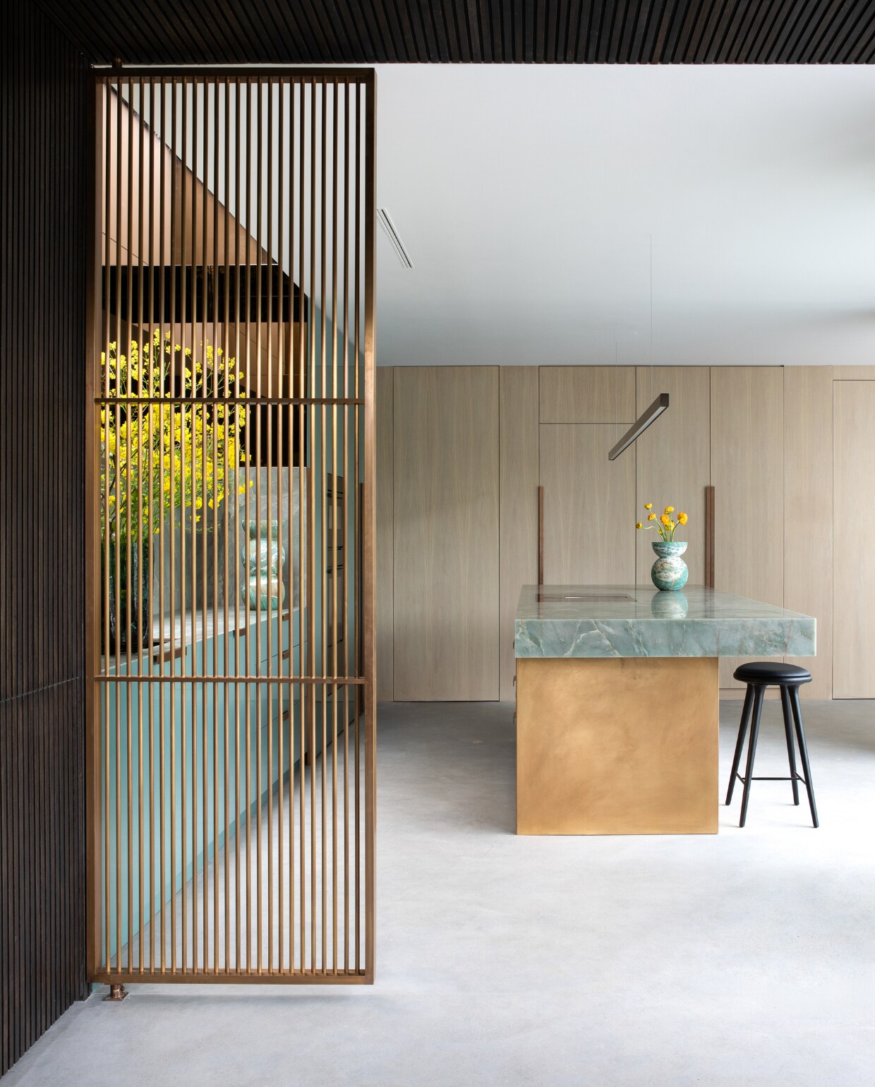 De keuken heeft een lange apparatenwand in licht eiken, afgewerkt met dezelfde koperen handgrepen als de turquoise kasten. De schermen zijn met minimale bevestigingen tussen vloer en plafond geklemd. stijlvol wonen 01-2025 | productie Living Inside | fotografie Ruth Maria Murphy