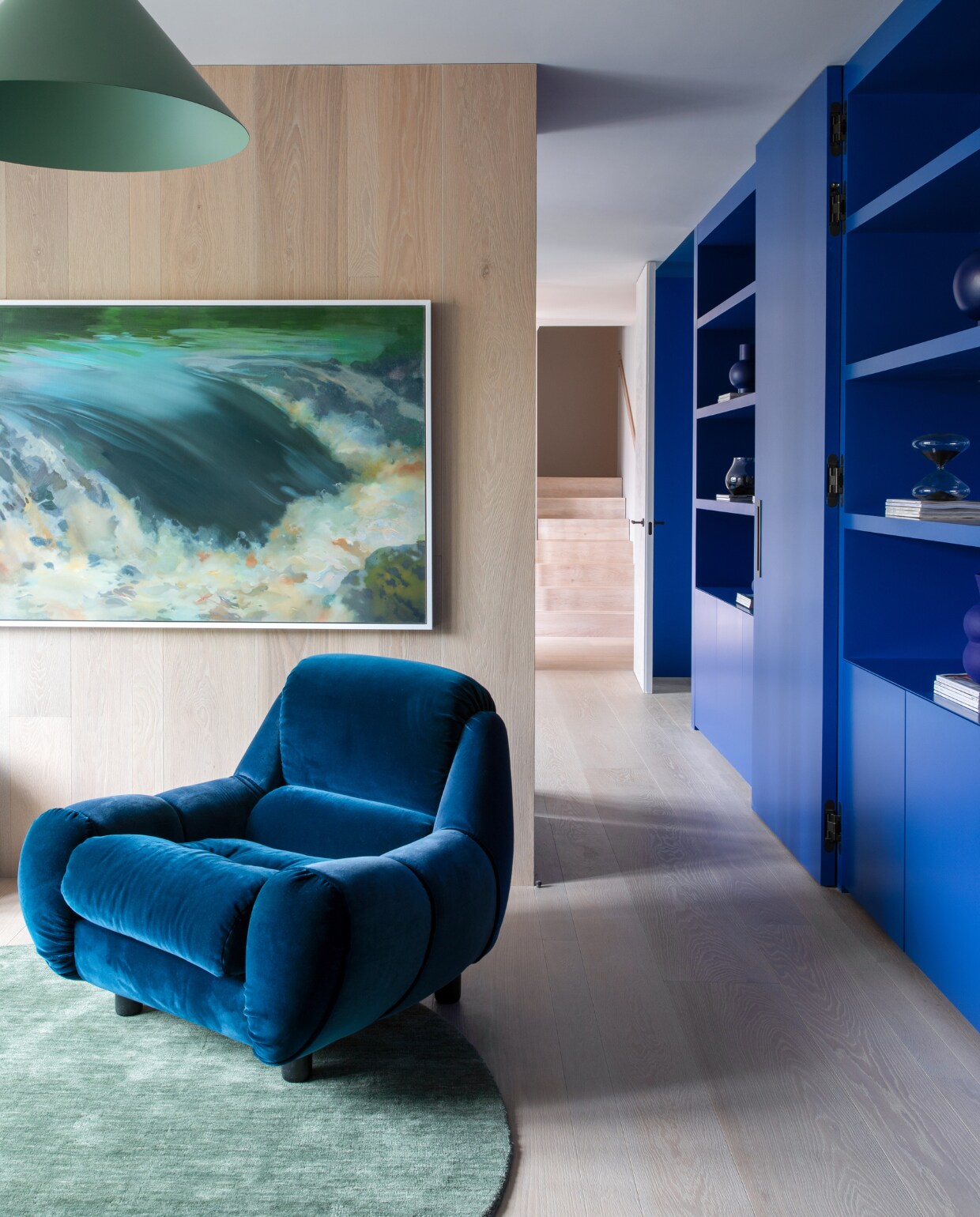 Schilderij A River Runs Through It van Paul Kerr. Hanglamp Konko van Loftlight, vloerkleed Rugvista. De blauwe fauteuil had het gezin al en is opnieuw bekleed. stijlvol wonen 01-2025 | productie Living Inside | fotografie Ruth Maria Murphy