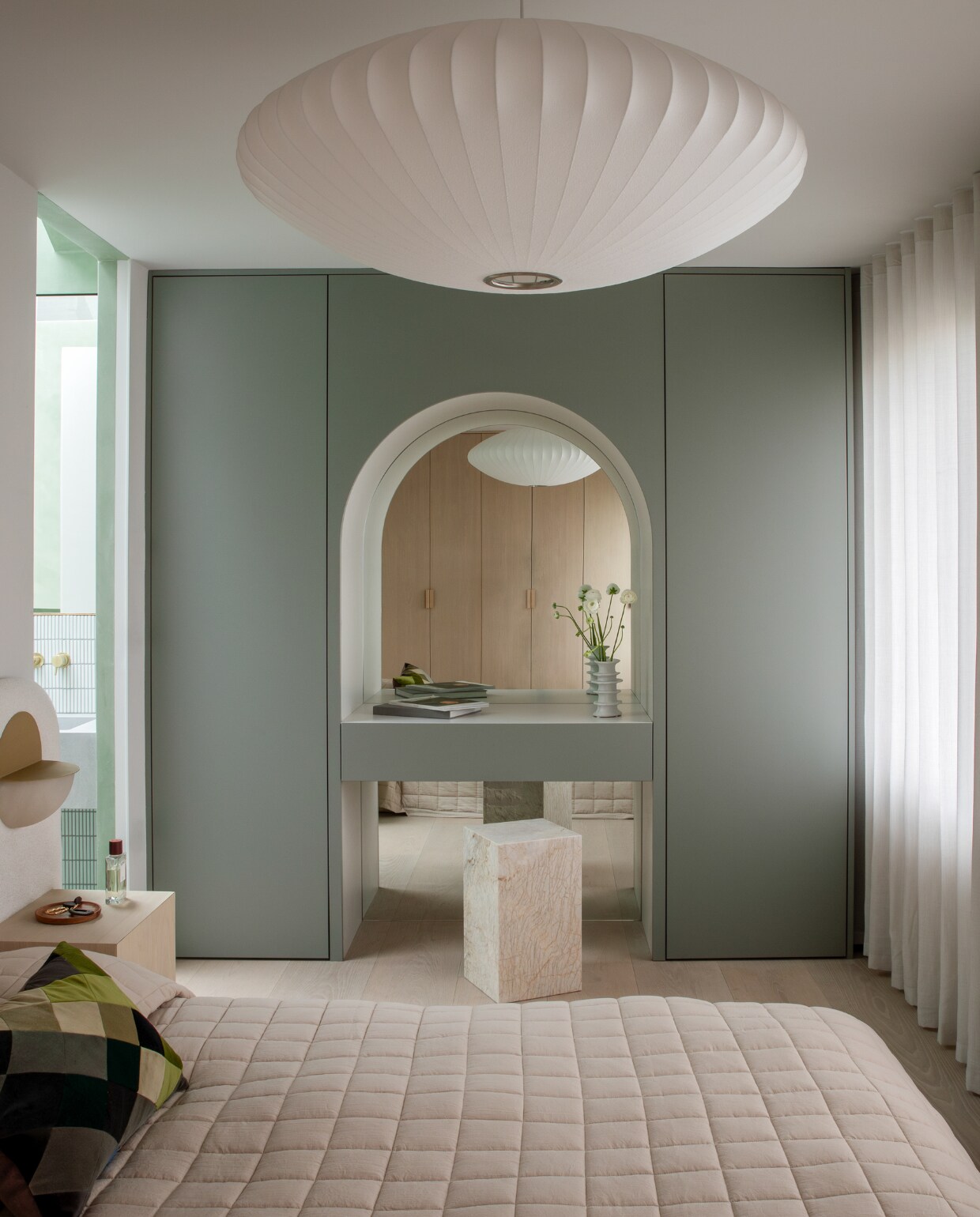 Het bedframe is op maat gemaakt en gestoffeerd door The Ripple Furniture Co. Wandlampen Luno van Simone &amp; Marcel, hanglamp Nelson Saucer Bubble van Hay. Dankzij de spiegel in de poortvormige nis van de toilettafel lijkt de ruimte door te lopen. stijlvol wonen 01-2025 | productie Living Inside | fotografie Ruth Maria Murphy