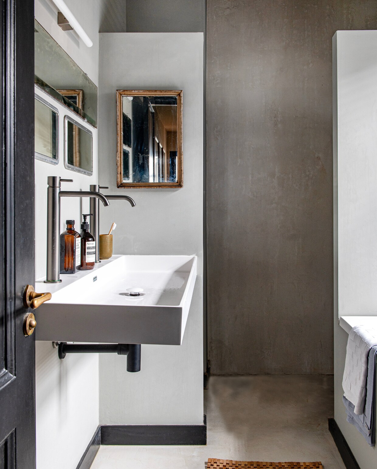 Wasbak, kranen en badmat Tortu World, spiegels kringloop, wandafwerking beton ciré, deurbeslag zat er al, muurverf Lamp Room Gray van Farrow &amp; Ball. vtwonen 01-2025 | productie De Binnenkijkers | fotografie Caroline Coehorst