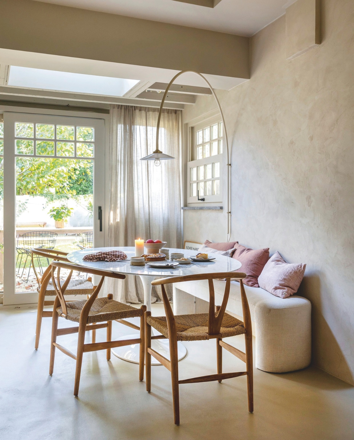 Fammeke en Neil geven graag etentjes voor vrienden. Om ruimte te besparen, kozen ze voor een eettafelbank. De Wishbone stoelen zijn van Carl Hansen, de ovale, marmeren tafel van Eero Saarinen en de wandlamp van Valerie Objects. Het servies is deels zelfgemaakt, deels van keramistSara Delesie. vtwonen landelijk 01-2025 | fotografie Sarah van Hove